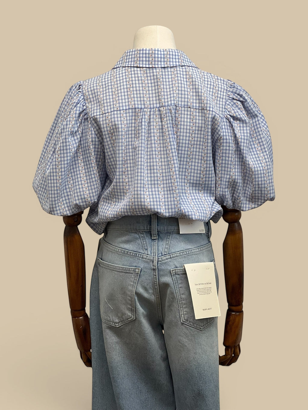 Homestyle Collective blue and white gingham blouse with puff sleeves and floral detail. Back view.