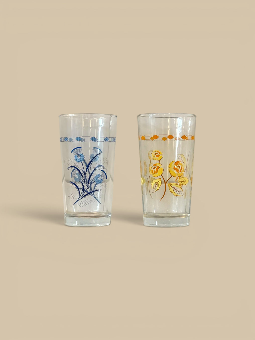 Homestyle Collective set of 2 clear glass tumblers with blue thistle and yellow rose floral patterns.