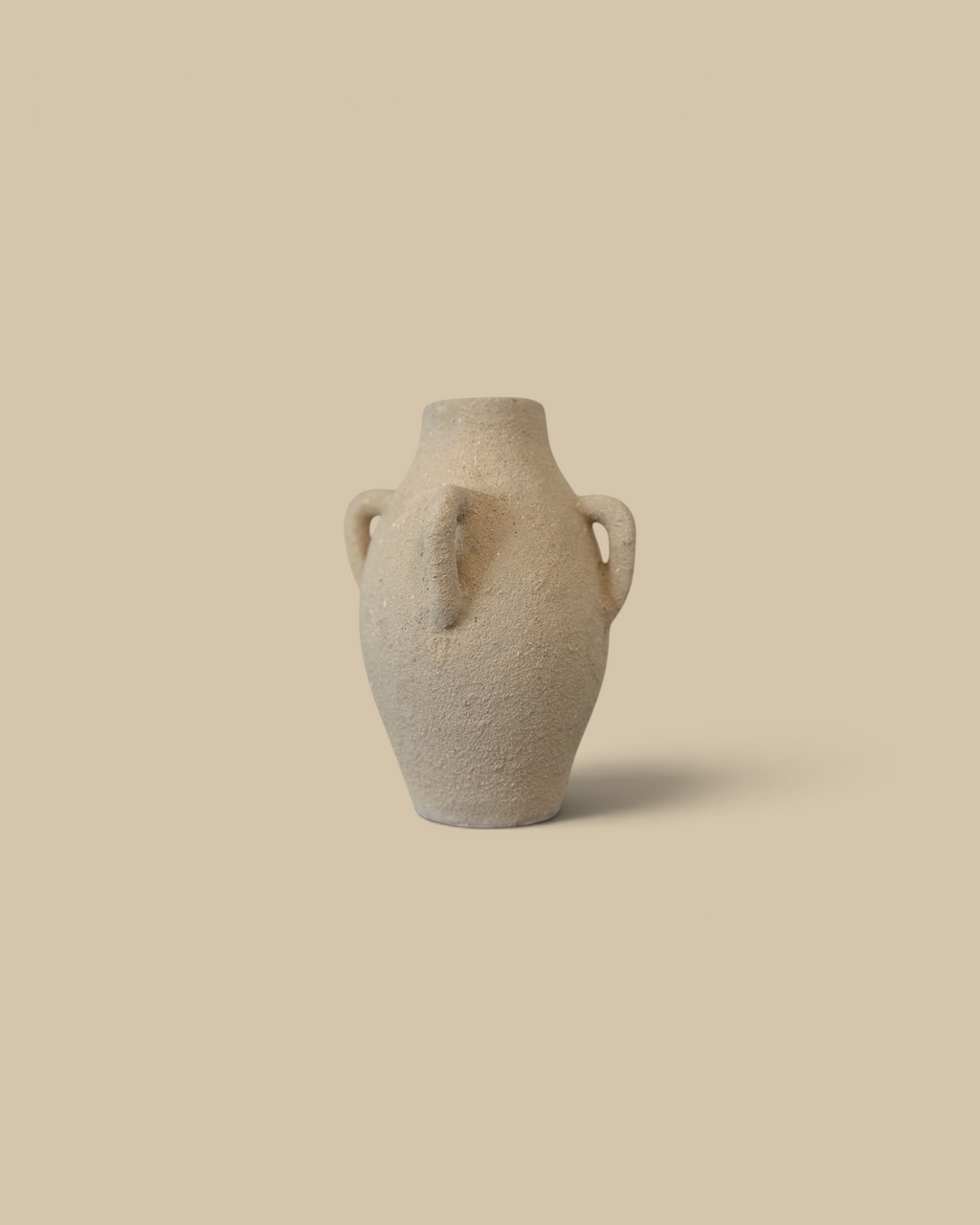 Homestyle Collective cream handcrafted clay vase with four handles on a marble shelf against a white tiled wall