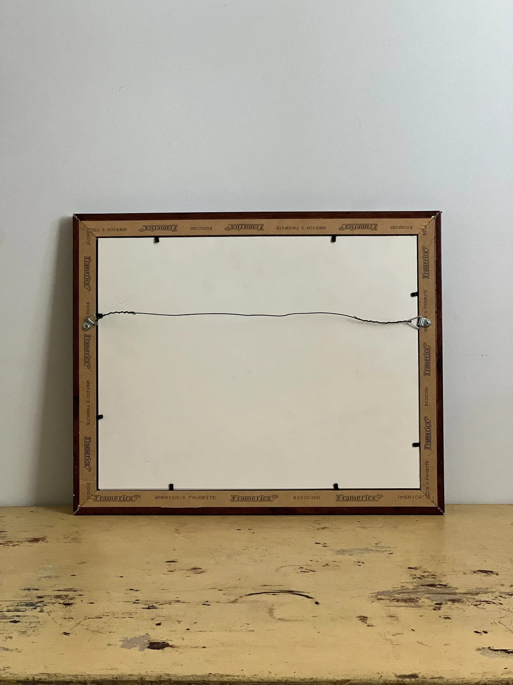 Homestyle Collective framed advertisement with a dark wood frame and wire hanging hardware.