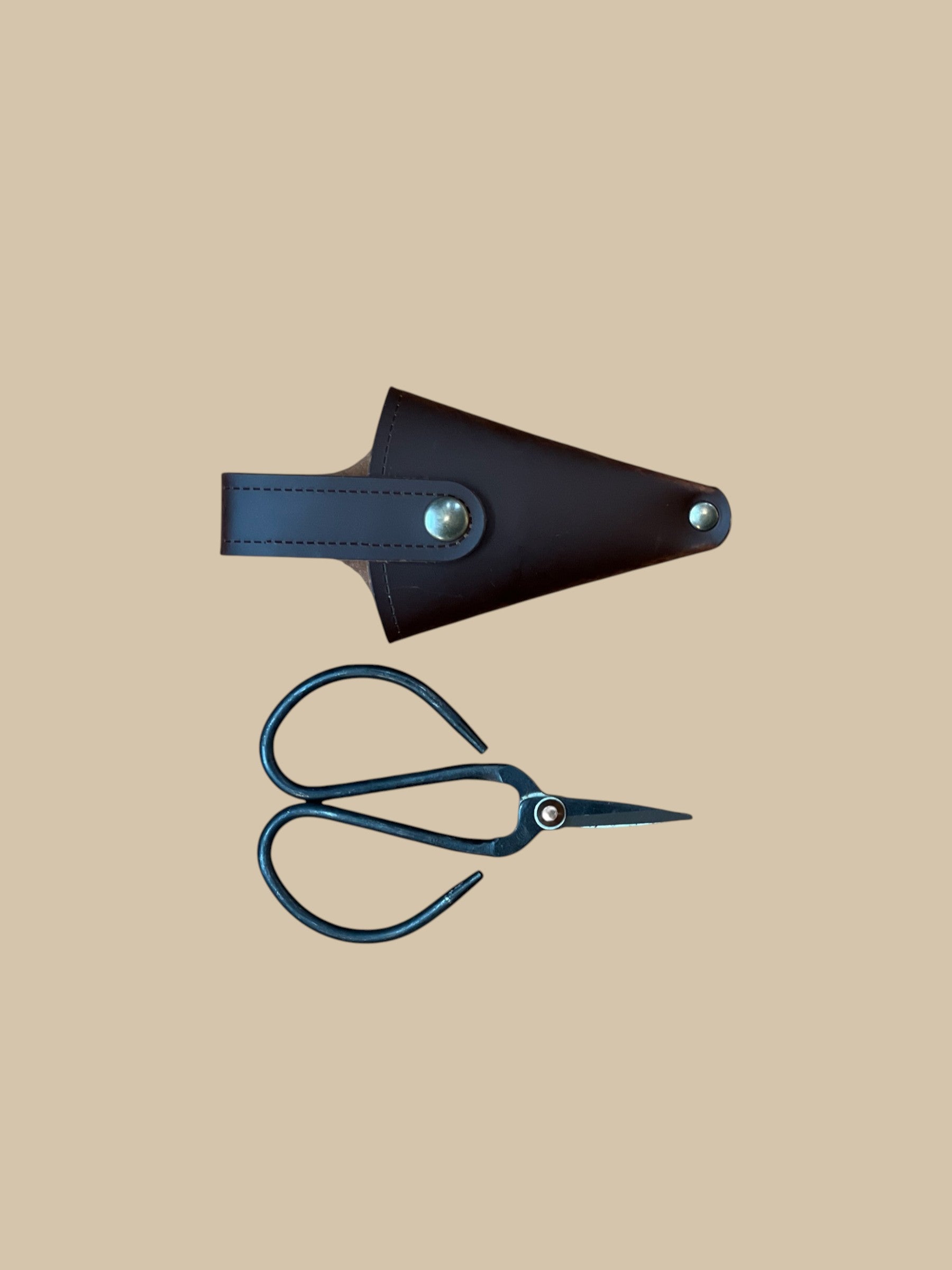 Homestyle Collective black metal pocket pruner snips with dark brown leather pouch, ideal for gardening and floral arrangements.