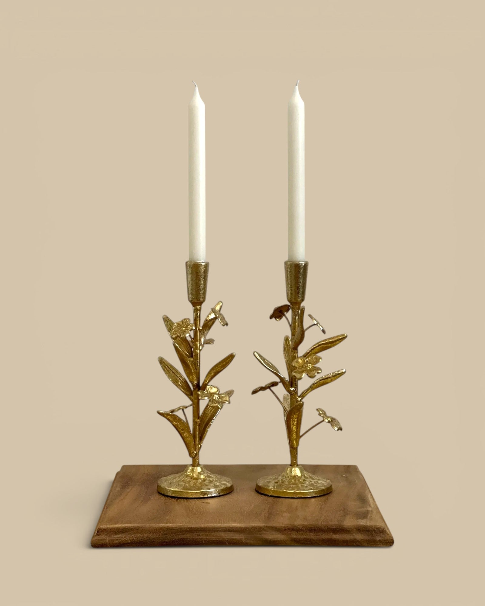 Homestyle Collective gilded floral candle holders with white taper candles. Metal with floral and leaf details.
