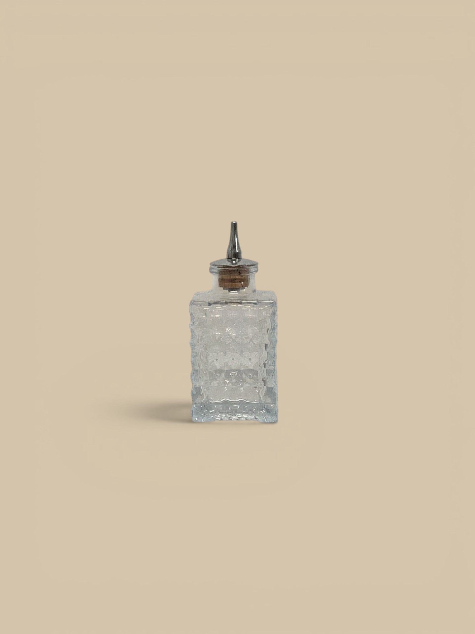 Homestyle Collective clear glass bitters bottles, one round and one square, with pour spouts.