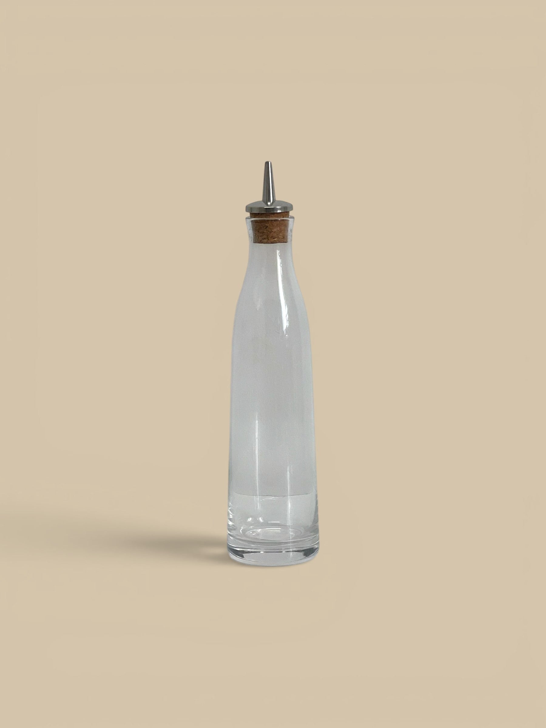 Homestyle Collective clear glass cruet with metal pour spout and cork stopper, ideal for oils, vinegars, or dressings.