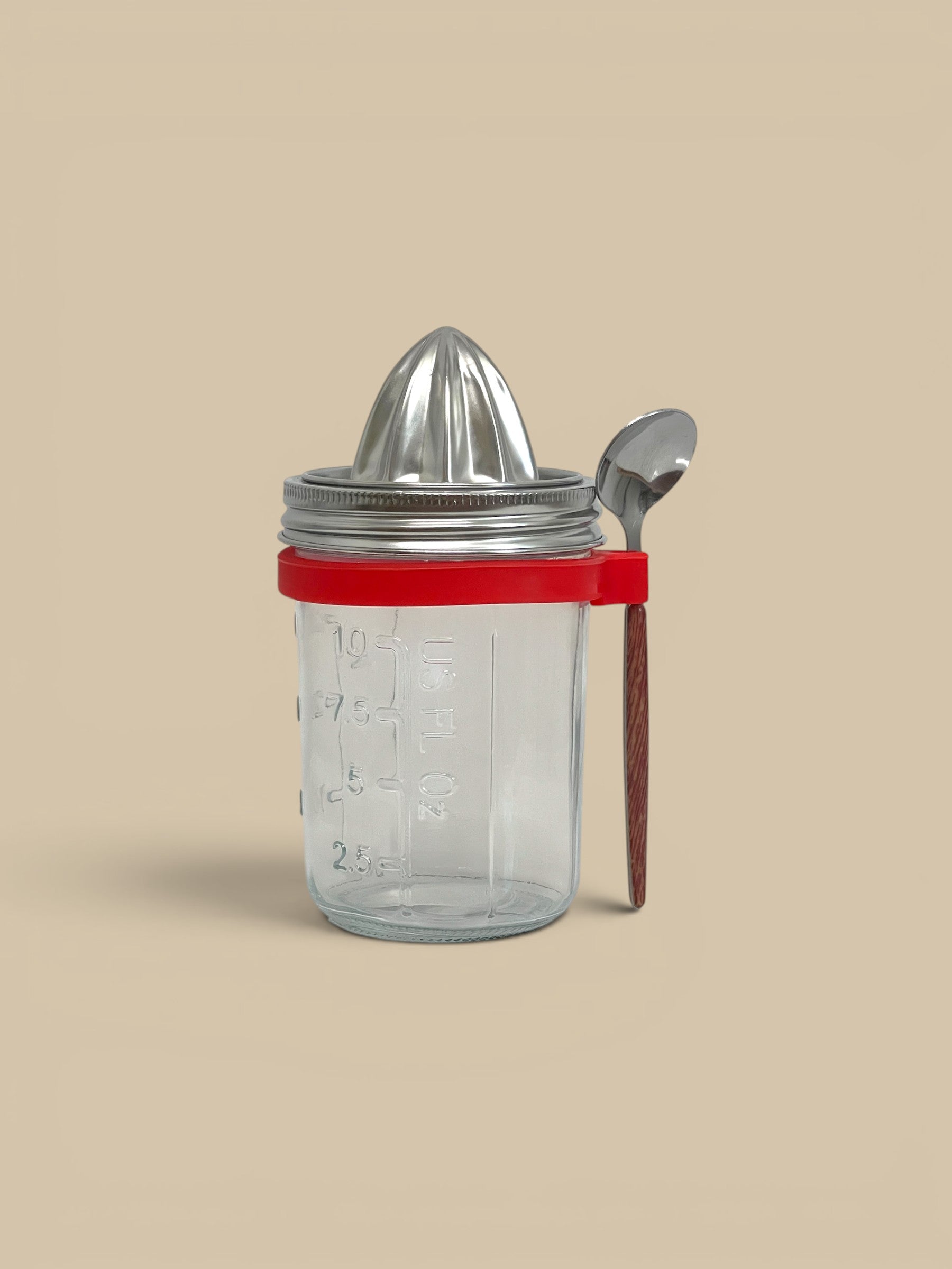Homestyle Collective glass juicer jar with stainless steel juicing attachment, spoon, and red silicone ring.