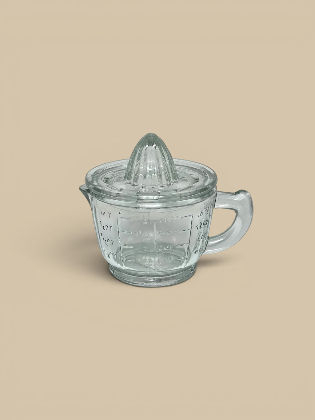Homestyle Collective clear pressed glass juicer with measuring cup base, featuring ridged top for citrus and measurement markings.