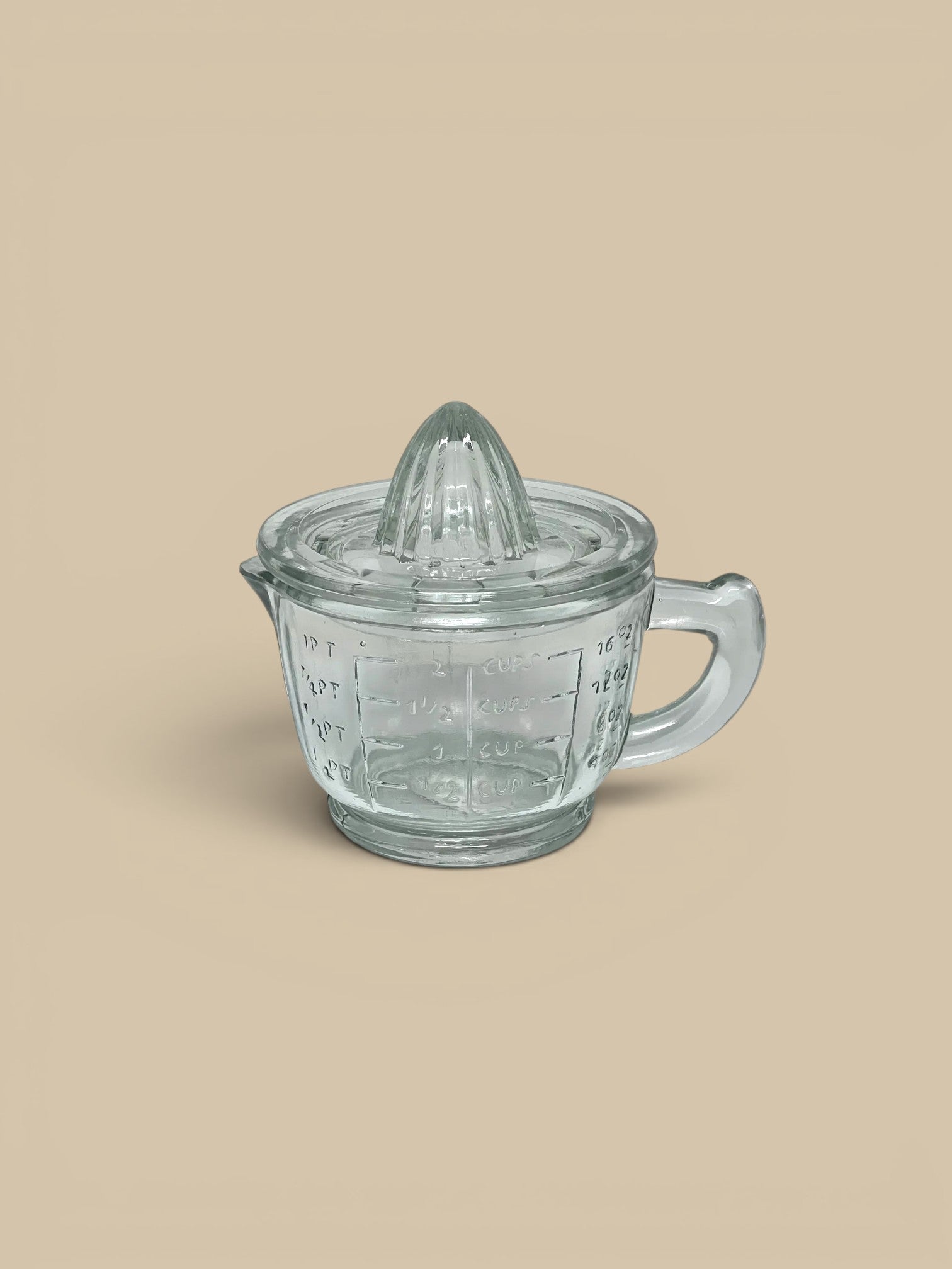 Homestyle Collective clear pressed glass juicer with measuring cup base, featuring ridged top for citrus and measurement markings.