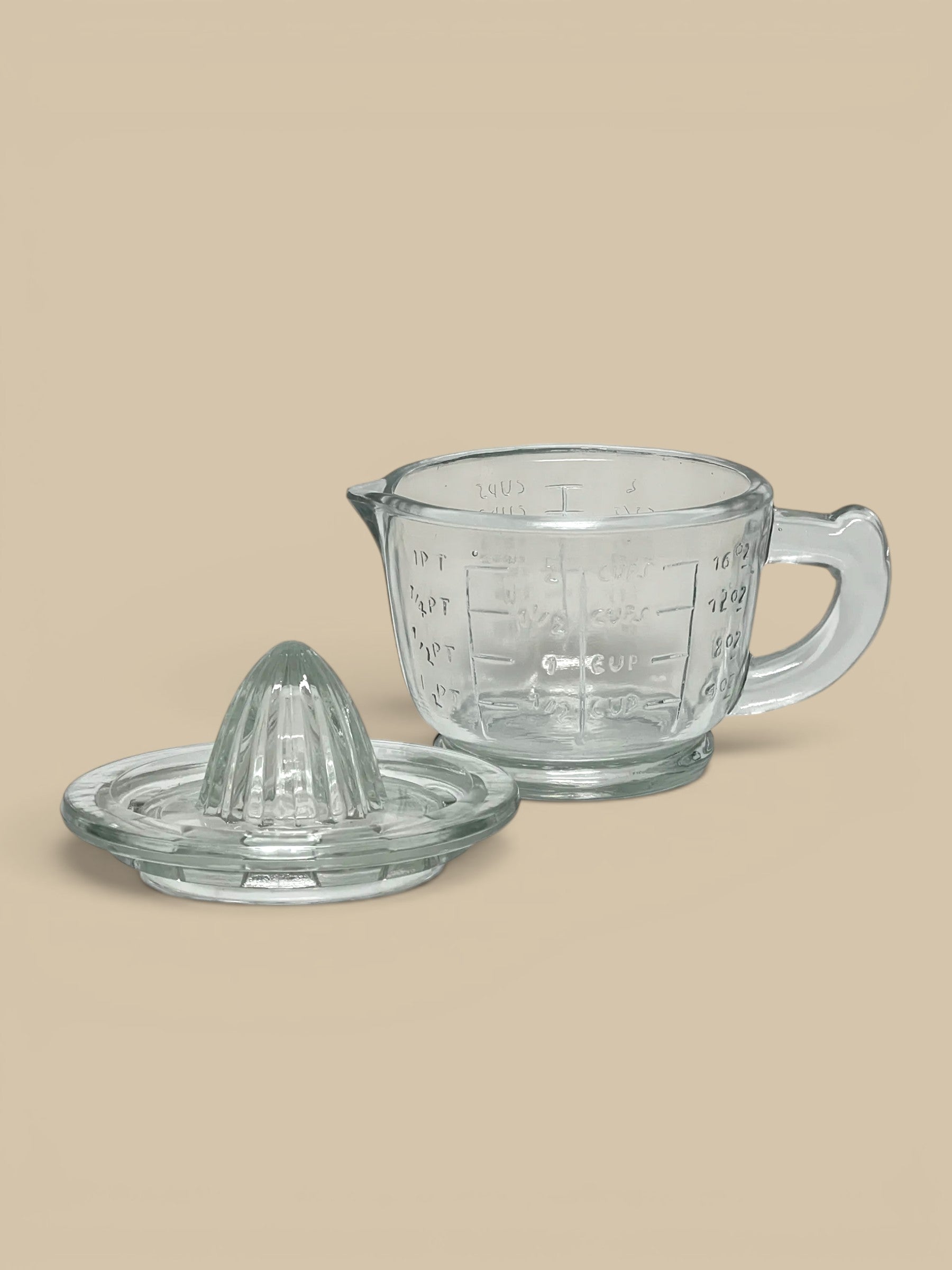 Homestyle Collective clear pressed glass juicer with ridged top and measuring cup base with embossed markings.