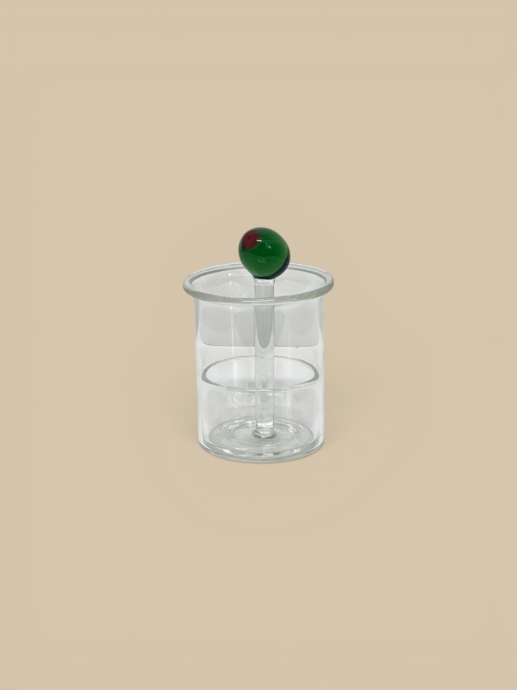 Homestyle Collective clear hand-blown glass toothpick holder with a green glass olive on top.