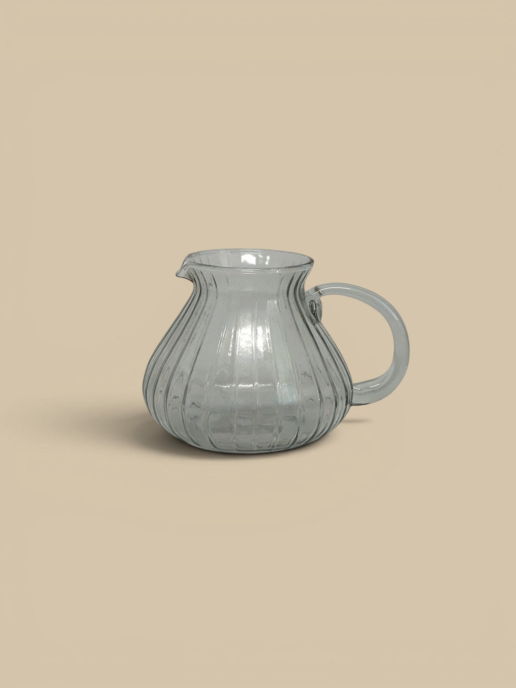 Homestyle Collective Ridgeline glass pitcher with subtle ribbed texture and a low profile. Clear grey glass.