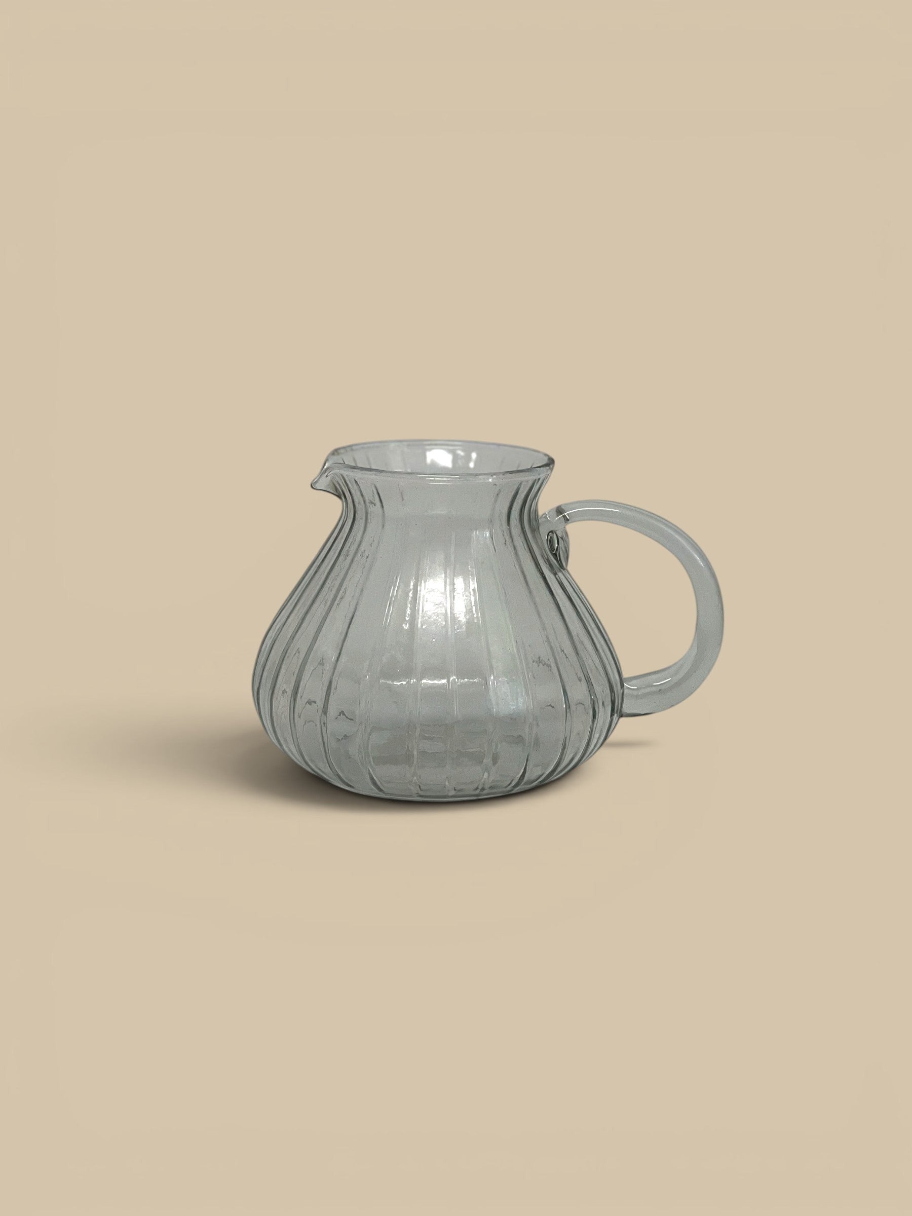 Homestyle Collective Ridgeline glass pitcher with subtle ribbed texture and a low profile. Clear grey glass.