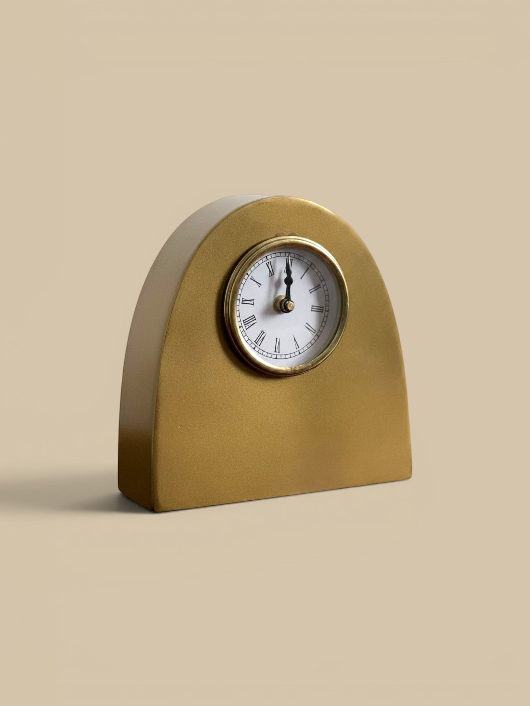 Homestyle Collective antique gold metal arch table clock with Roman numerals and white face.