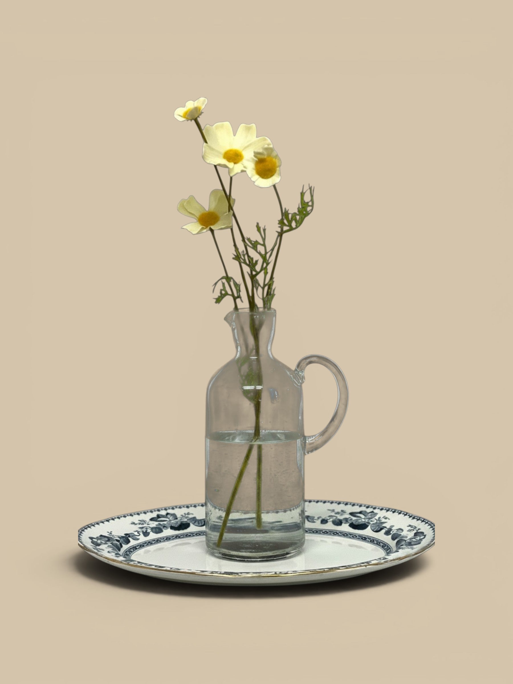 Homestyle Collective Santiago recycled glass carafe in grey with a handle, holding white flowers on a decorative tray.