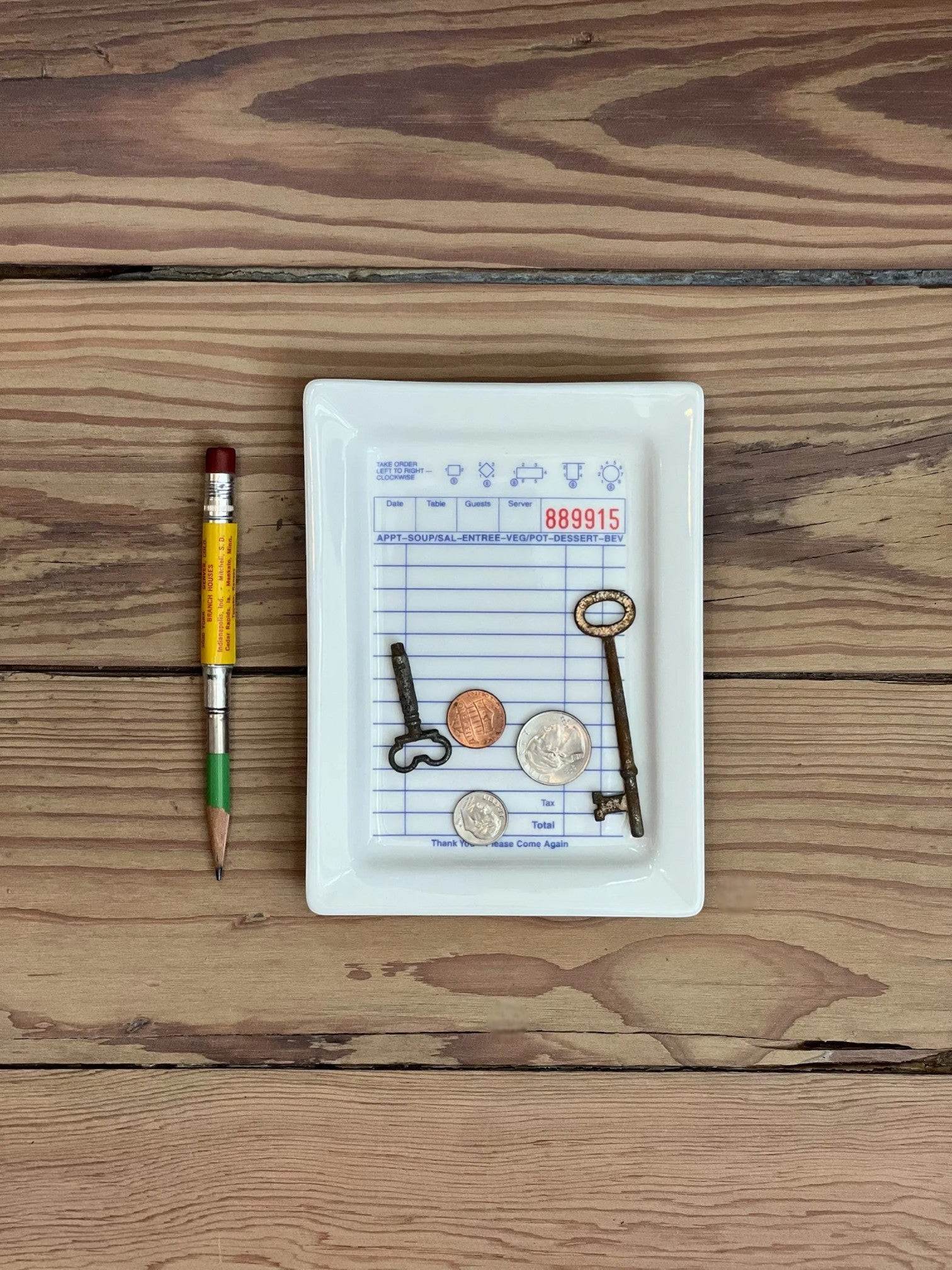 Homestyle Collective white ceramic tray with a guest check design, holding keys and coins.