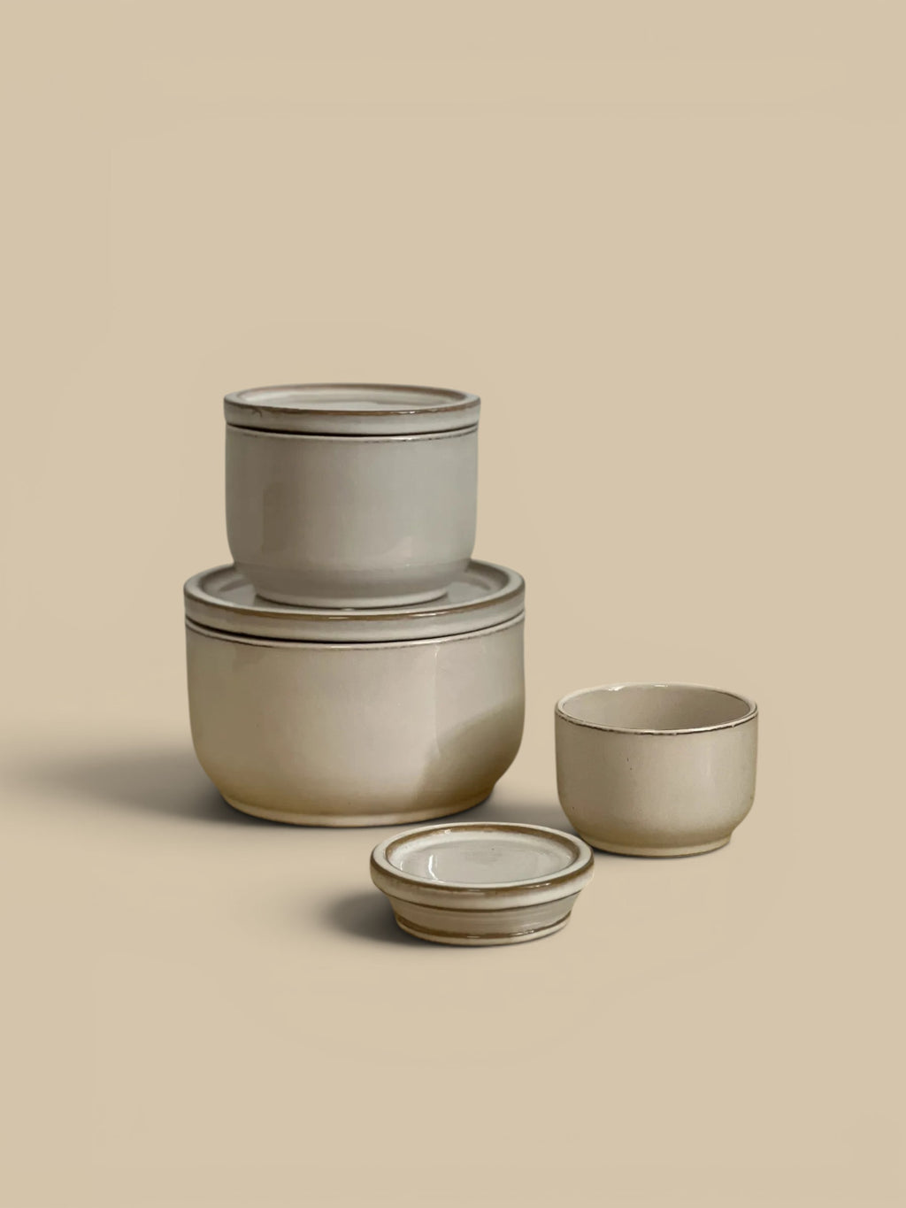 Homestyle Collective set of 3 ivory ceramic lidded jars with subtle brown trim. Classic design for kitchen or shelf decor.