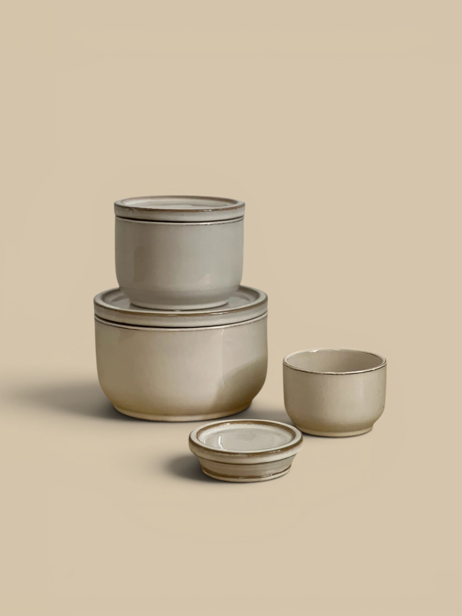 Homestyle Collective set of 3 ivory ceramic lidded jars with subtle brown trim. Classic design for kitchen or shelf decor.