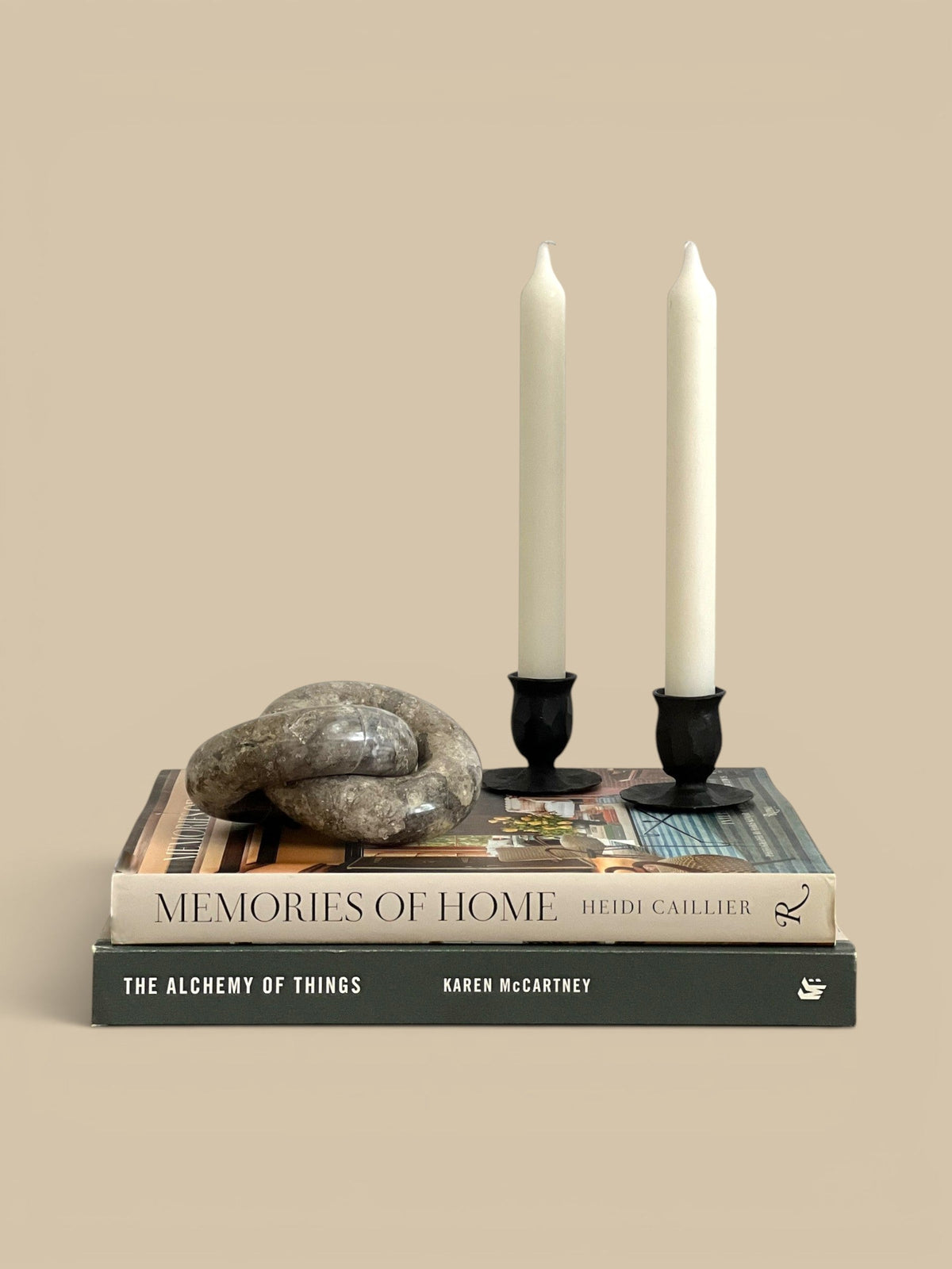 Homestyle Collective linked marble ring sculpture with brown veining on stacked books with two white candles.