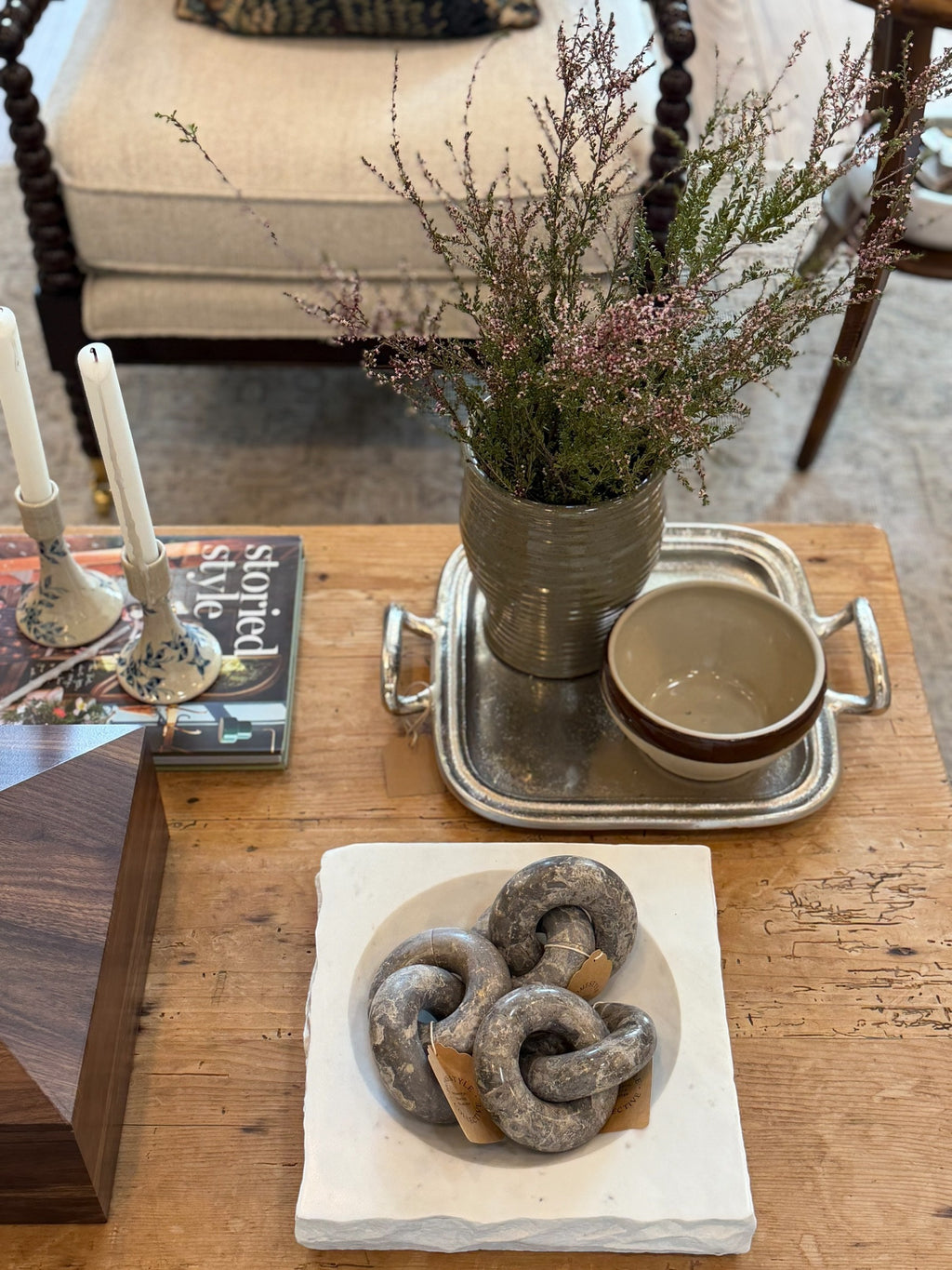 Homestyle Collective linked marble ring sculpture with brown veining displayed in a white stone bowl on a wooden table
