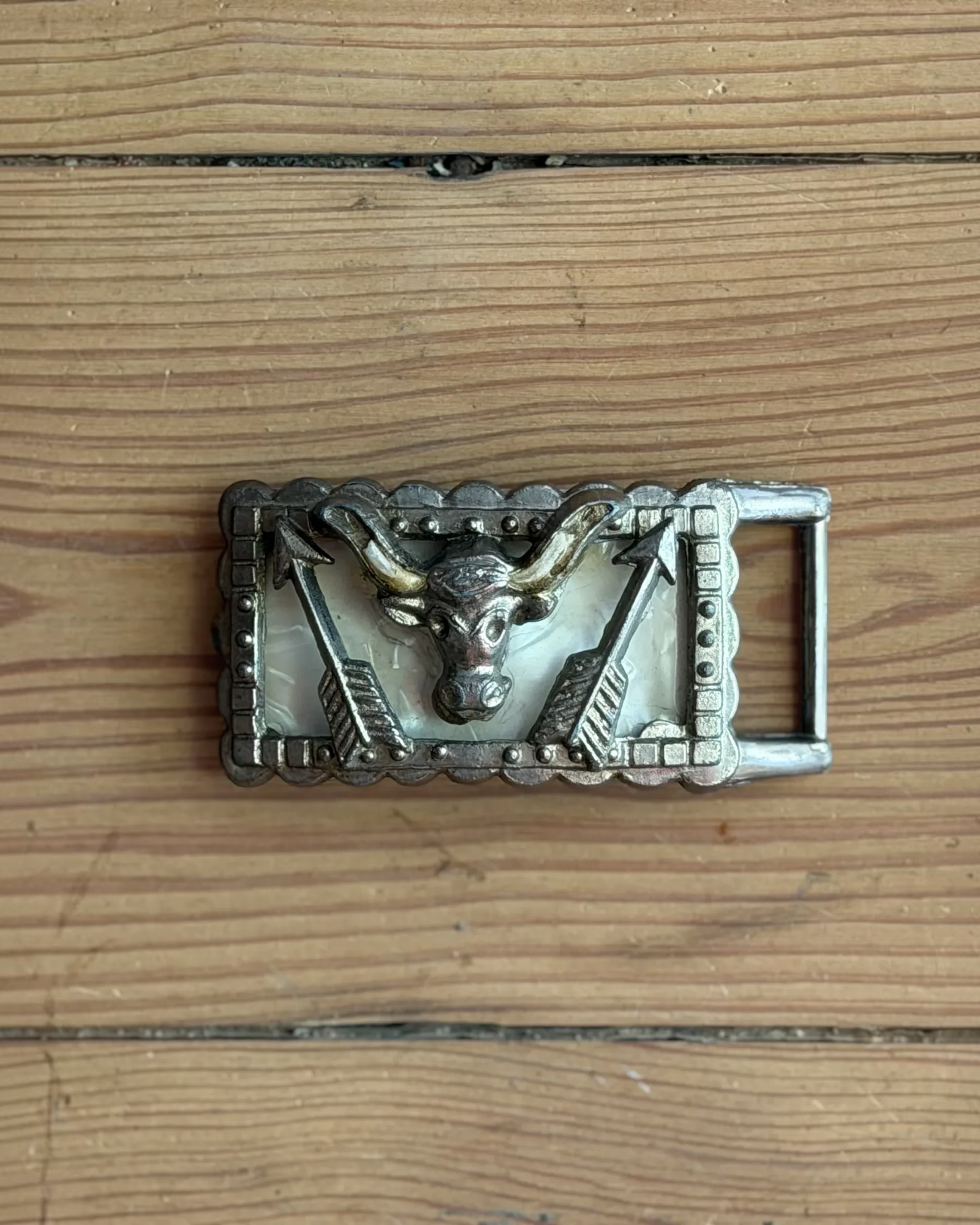 Homestyle Collective cast iron longhorn belt buckle with resin inlay and arrow accents on a wooden background