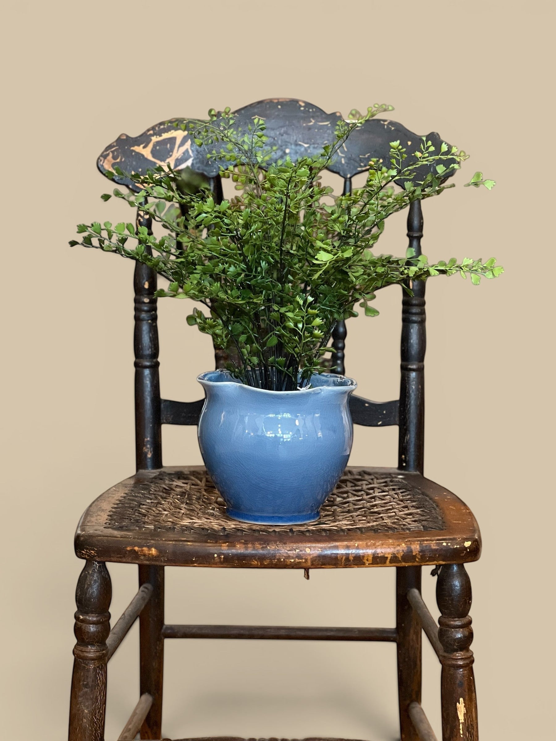 Homestyle Collective lifelike maidenhair fern in a blue ceramic pot on a vintage wooden chair.