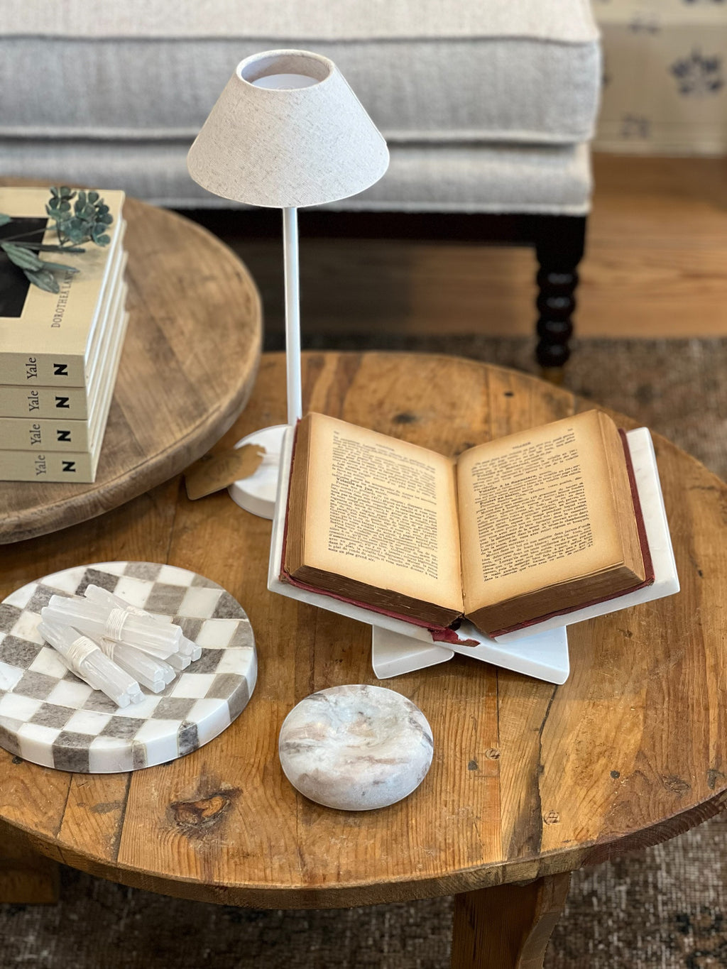 Homestyle Collective white marble book display holding an open antique book on a rustic wooden table.