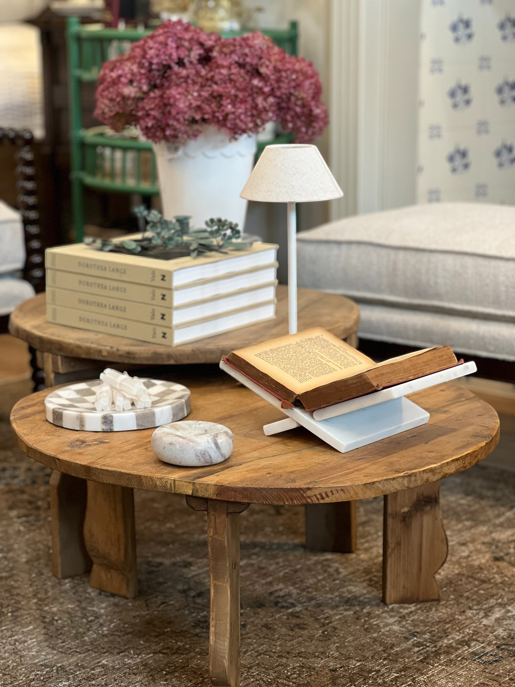 Homestyle Collective white marble interlocking book display holding an open book on a rustic wooden table.