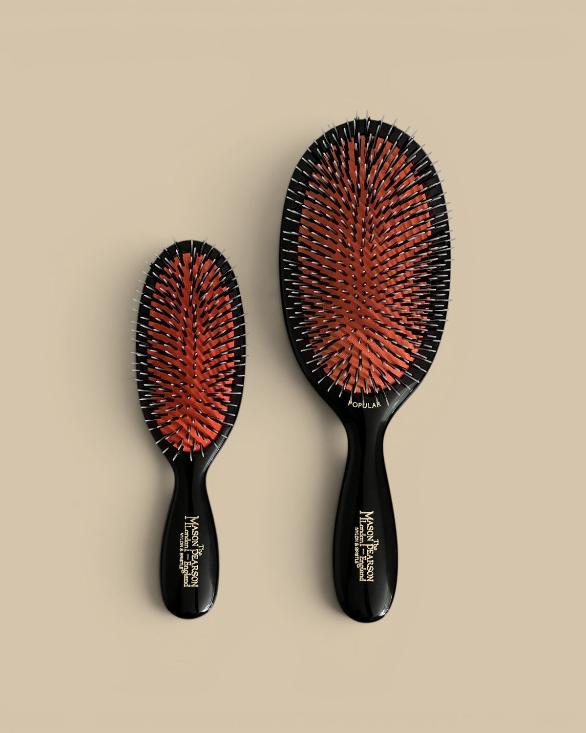 Homestyle Collective Mason Pearson Dark Ruby Pocket Brush and Popular Brush with black handles and orange rubber cushions.
