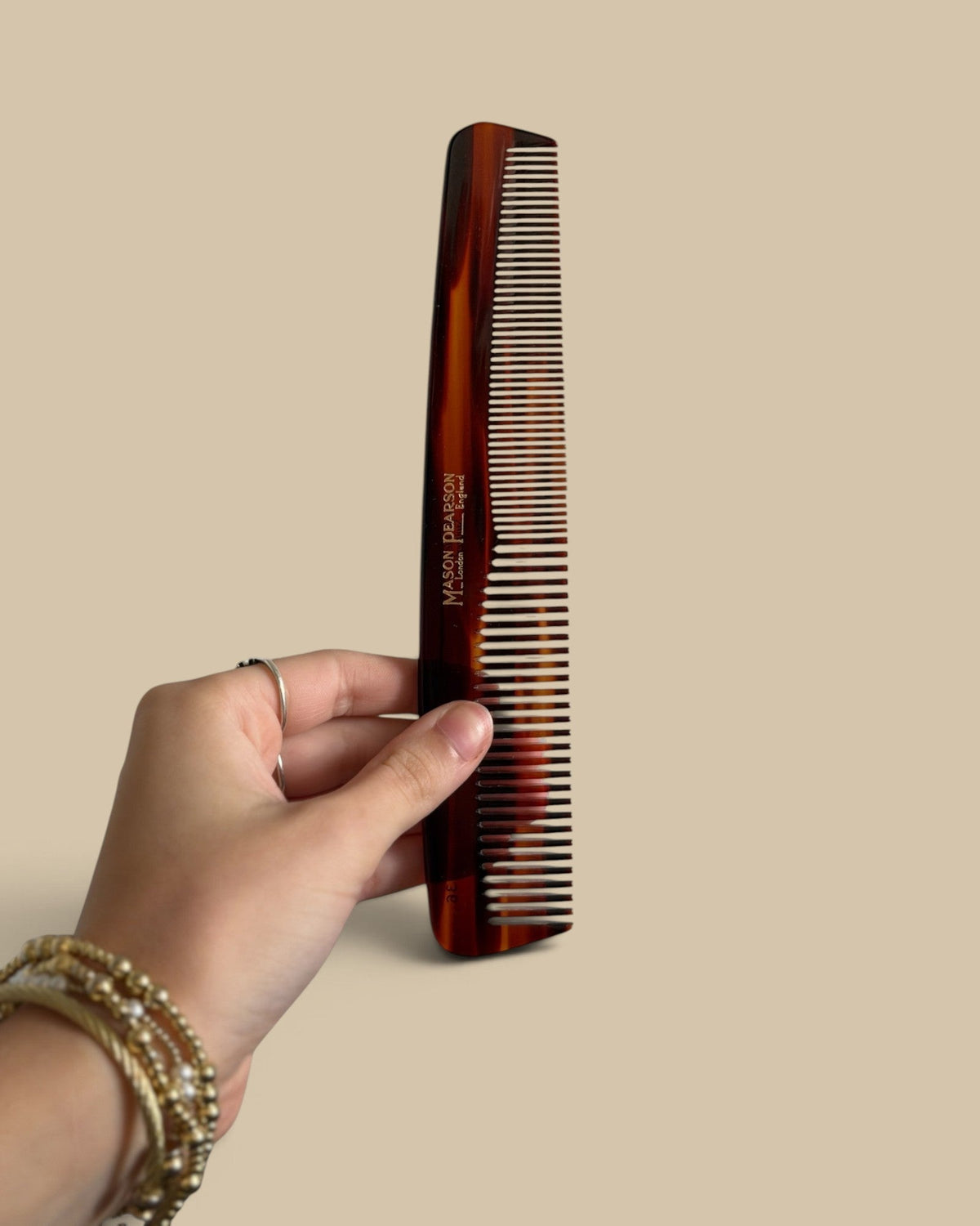 Homestyle Collective Mason Pearson dressing comb with tortoiseshell finish held in a hand for styling long hair