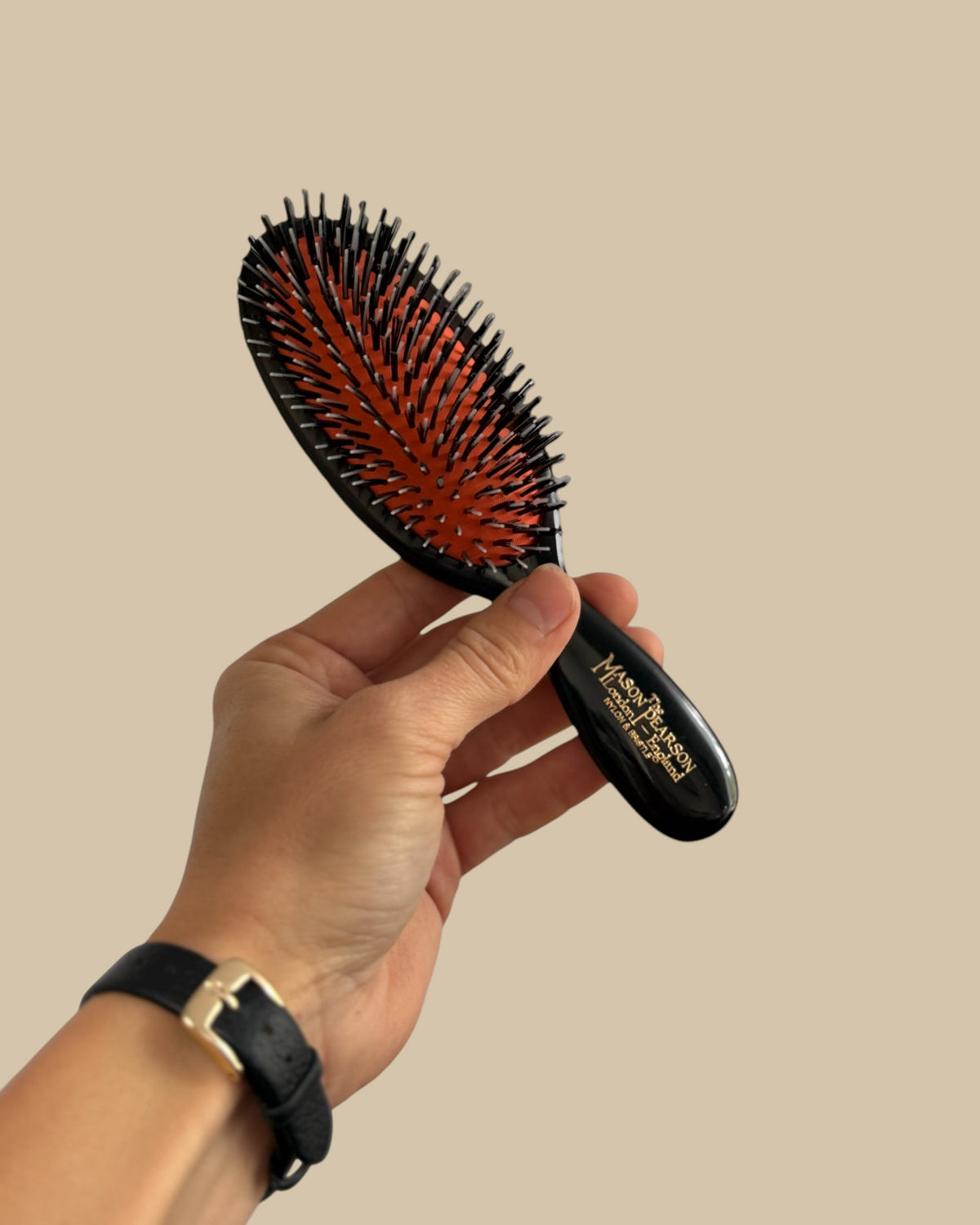 Homestyle Collective Mason Pearson pocket hairbrush in dark ruby with black nylon and boar bristles held in hand
