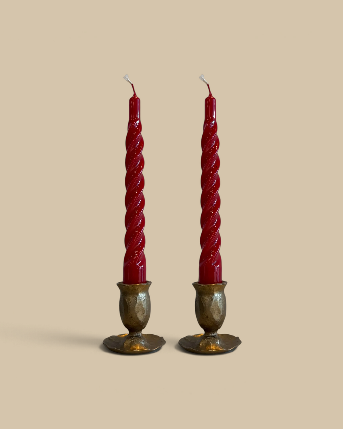 Homestyle Collective merlot red twisted taper candle with a glossy lacquered finish standing in a brass holder