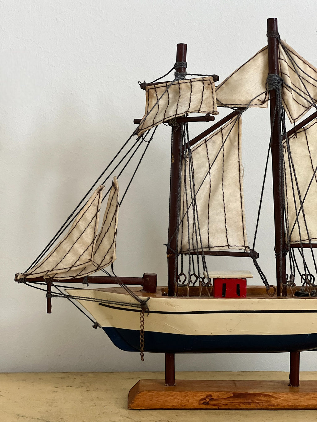 Homestyle Collective mini handmade wooden sailboat model with cream sails and blue hull, perfect for shelf styling.