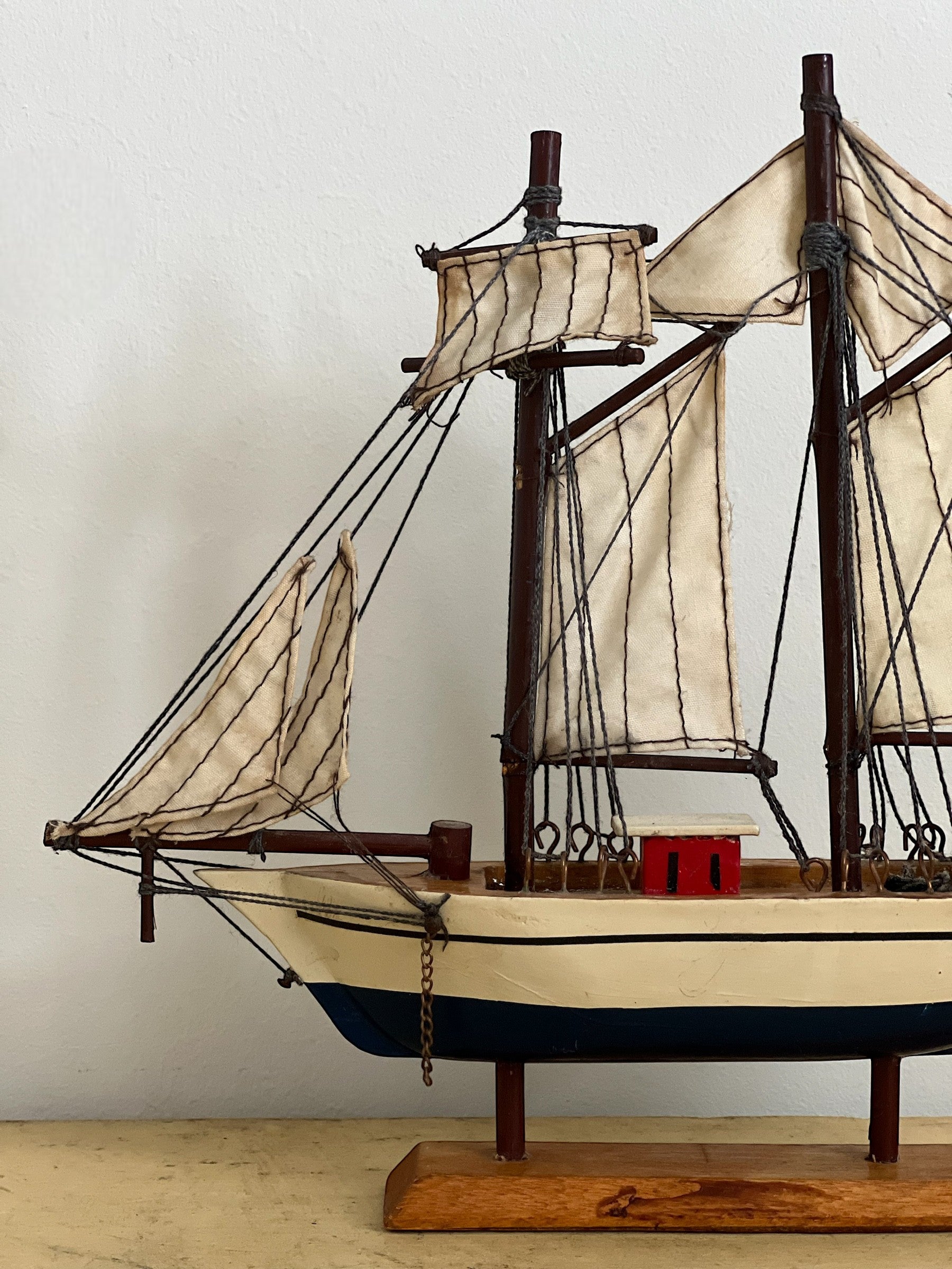 Homestyle Collective mini handmade wooden sailboat model with cream sails and blue hull, perfect for shelf styling.
