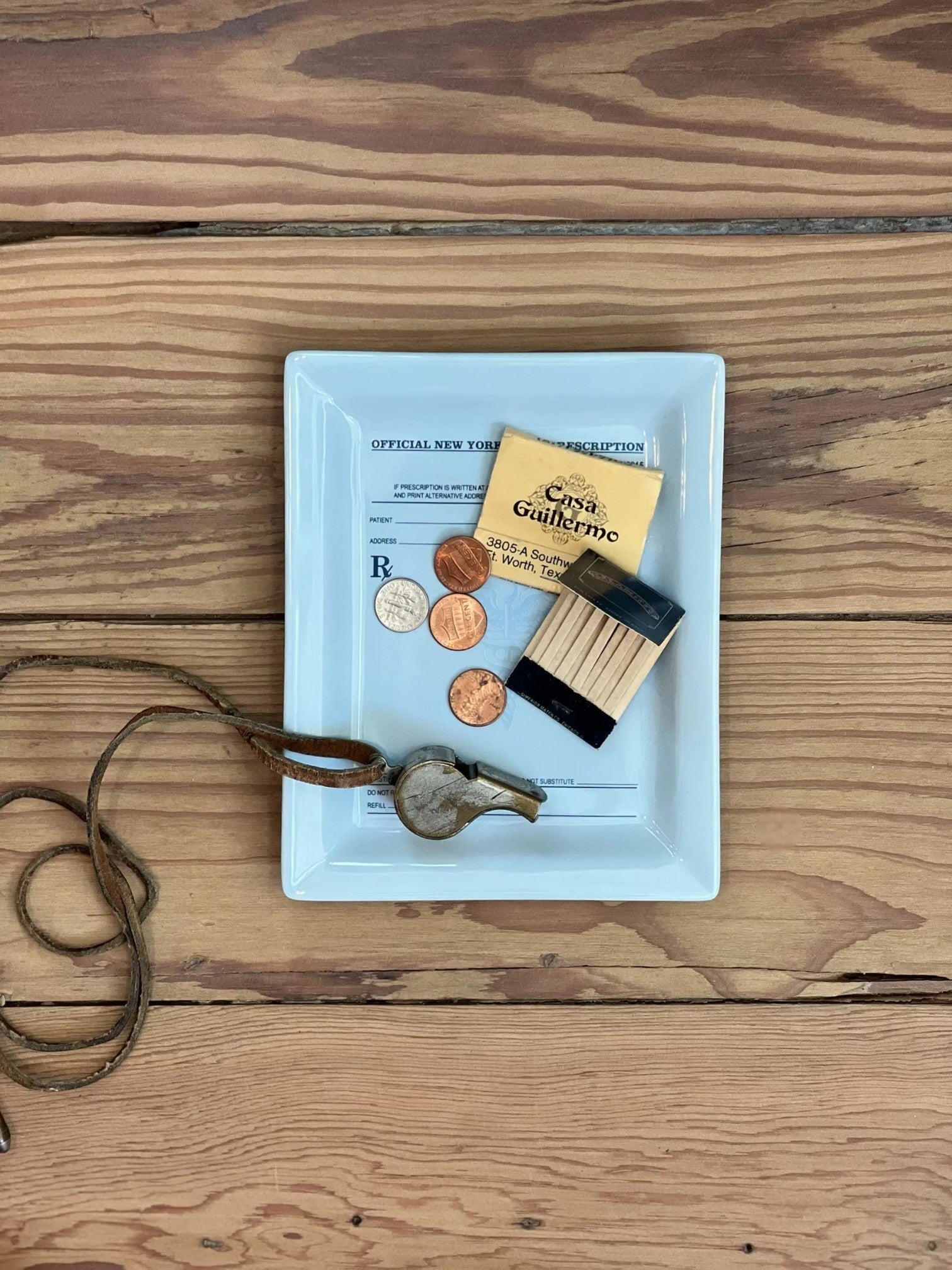 Homestyle Collective light blue ceramic catch-all tray with prescription design, holding coins, matches, and a whistle.