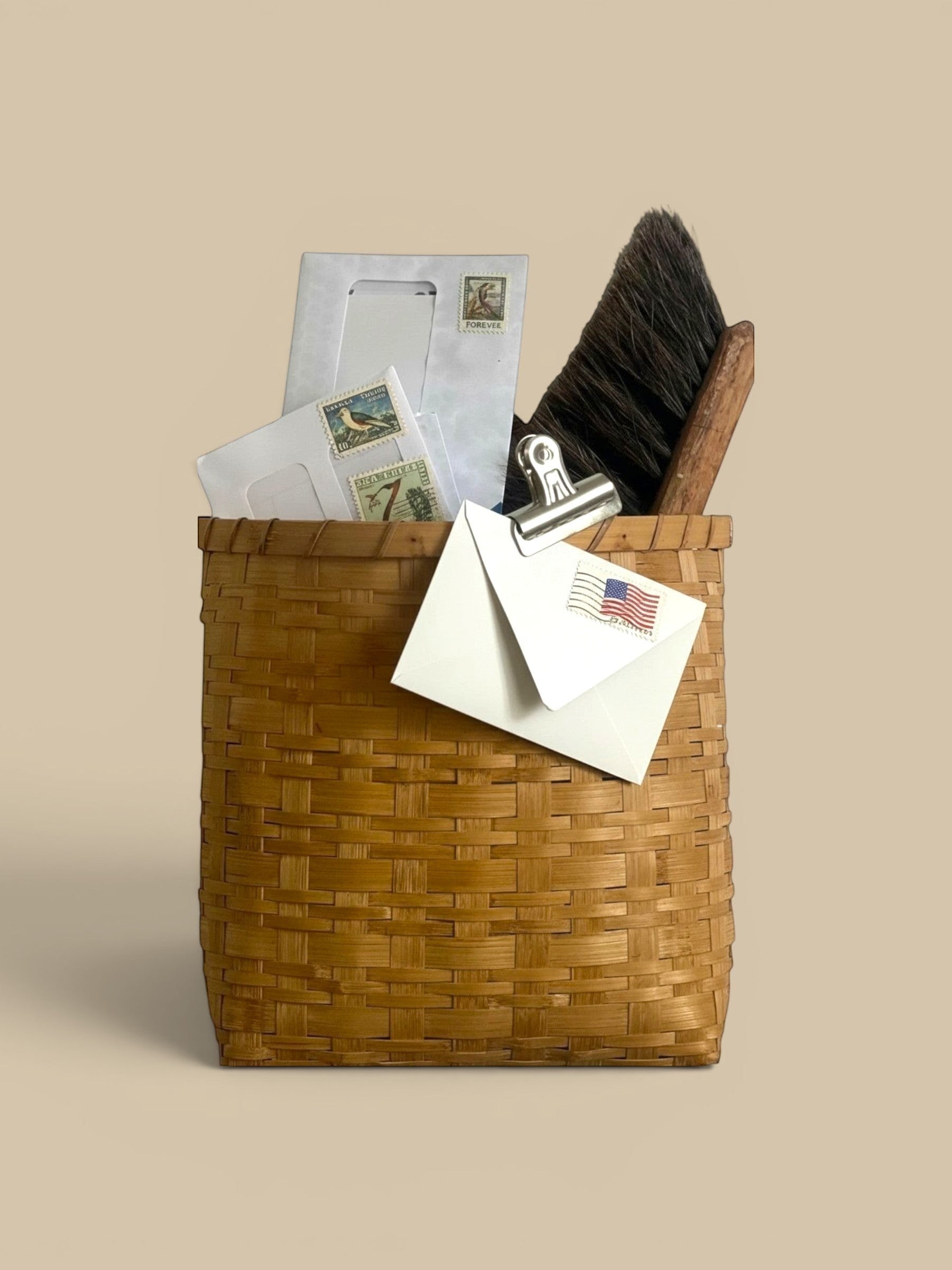 Homestyle Collective natural rattan hanging basket with flat back and built-in handle, holding mail and a brush.
