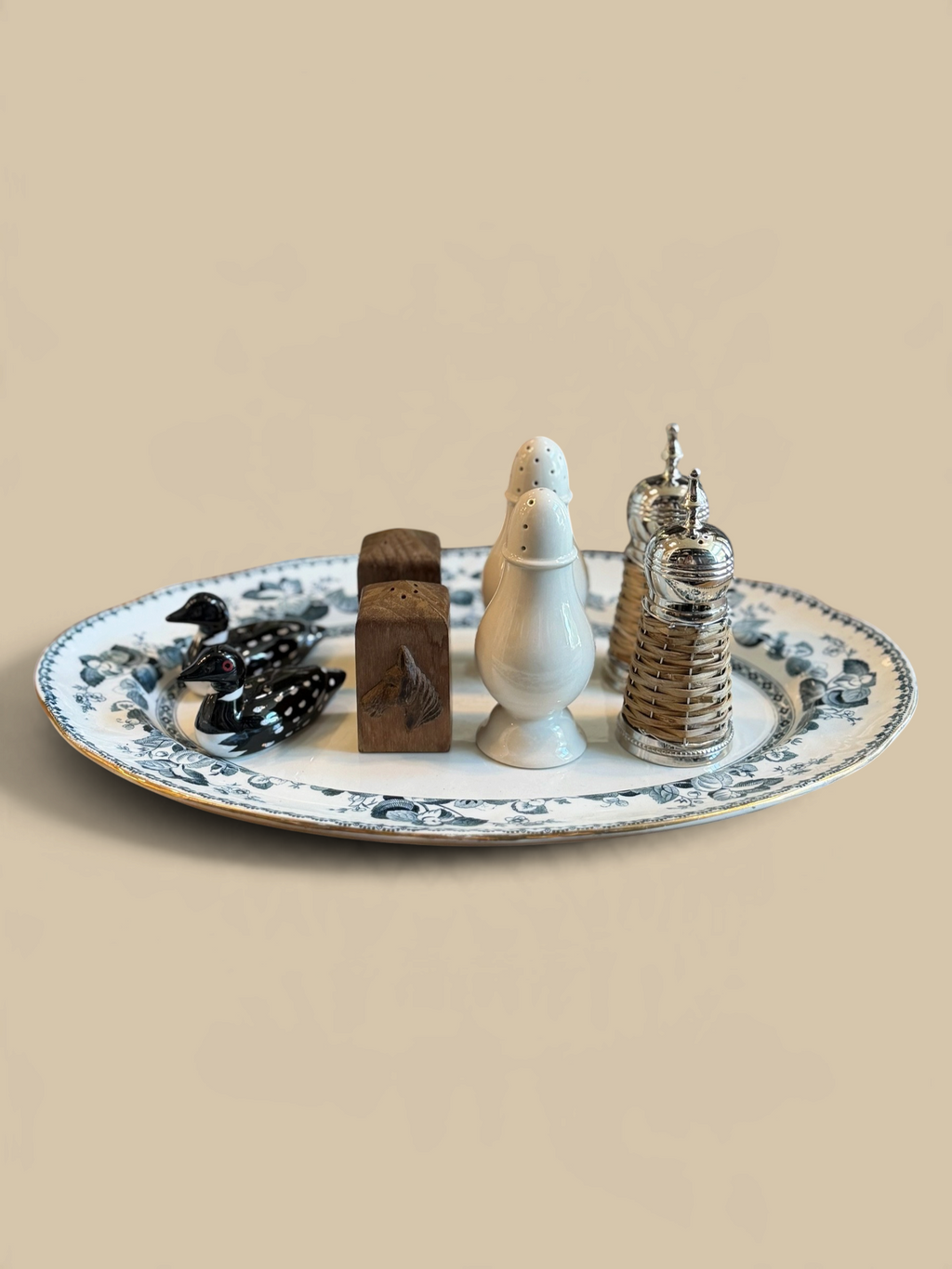 Homestyle Collective Cap Ferrat rattan and metal salt and pepper shakers on a decorative floral serving platter.