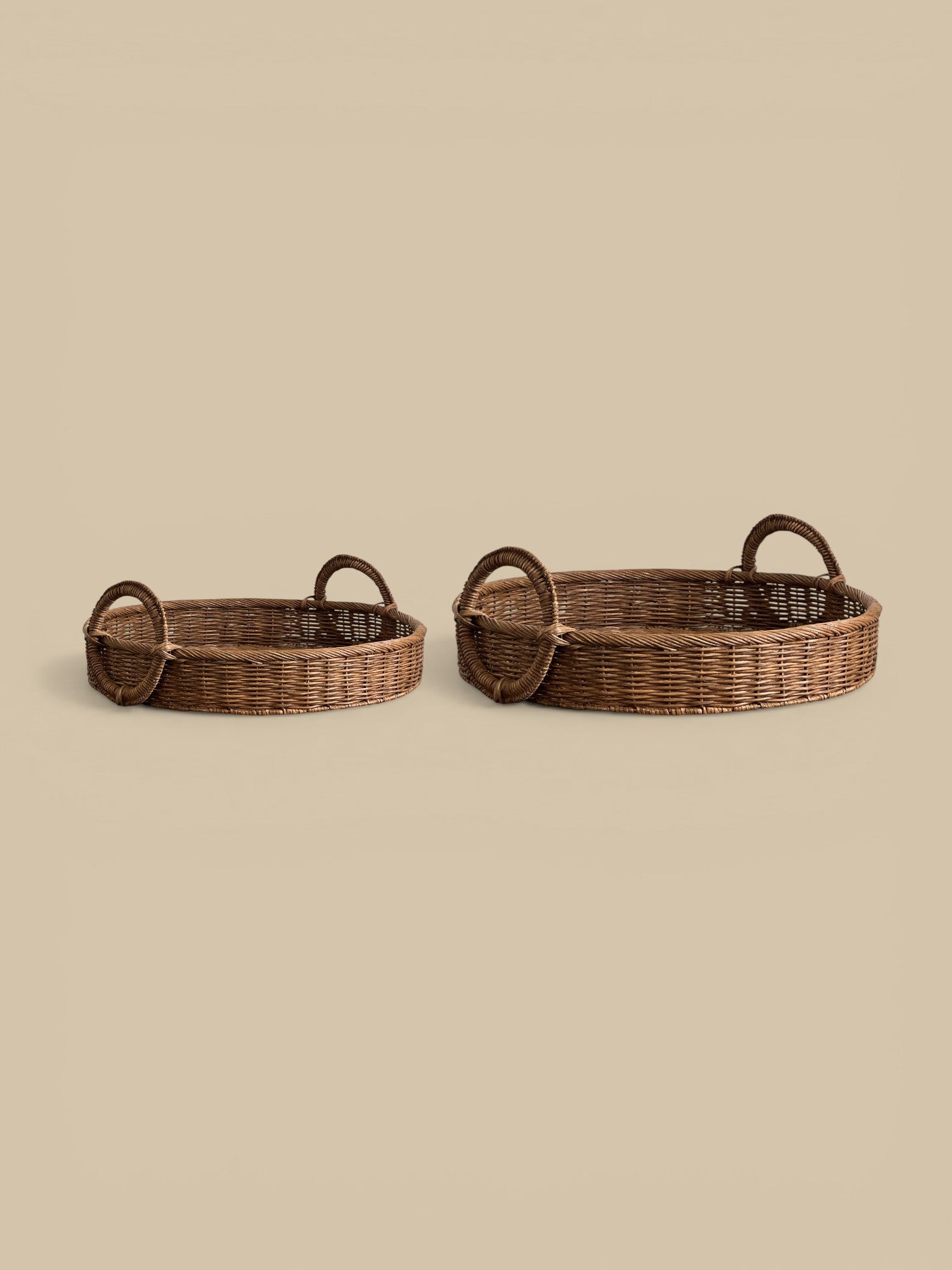 Homestyle Collective natural woven rattan oval tray with loop handles, set of 2. Warm organic finish.
