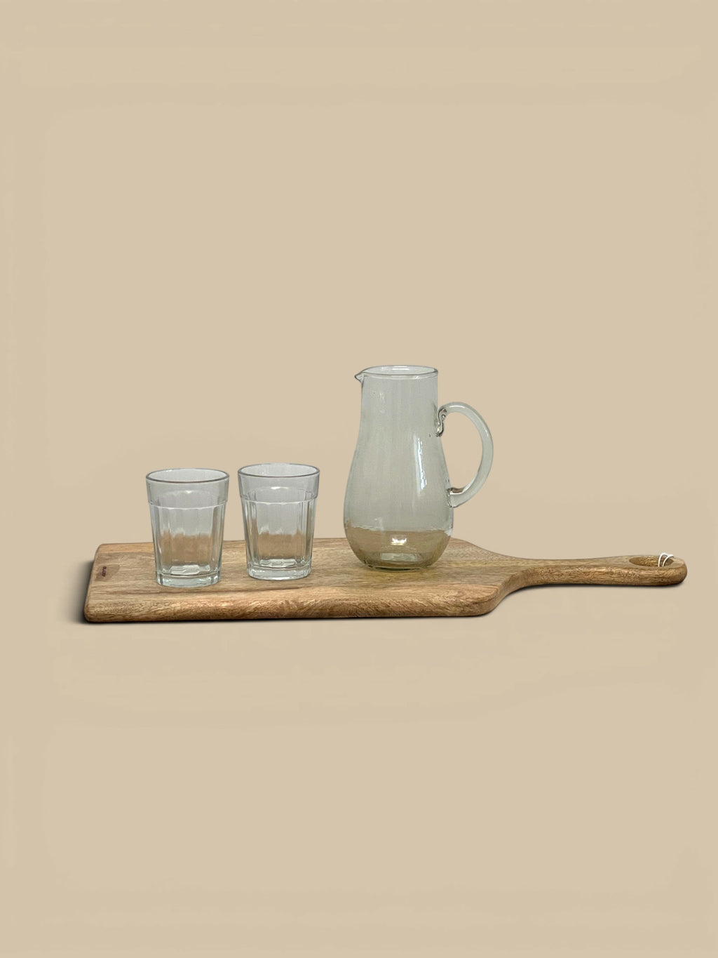 Homestyle Collective Minette ribbed glass pitcher and two small glasses on a wooden serving board.