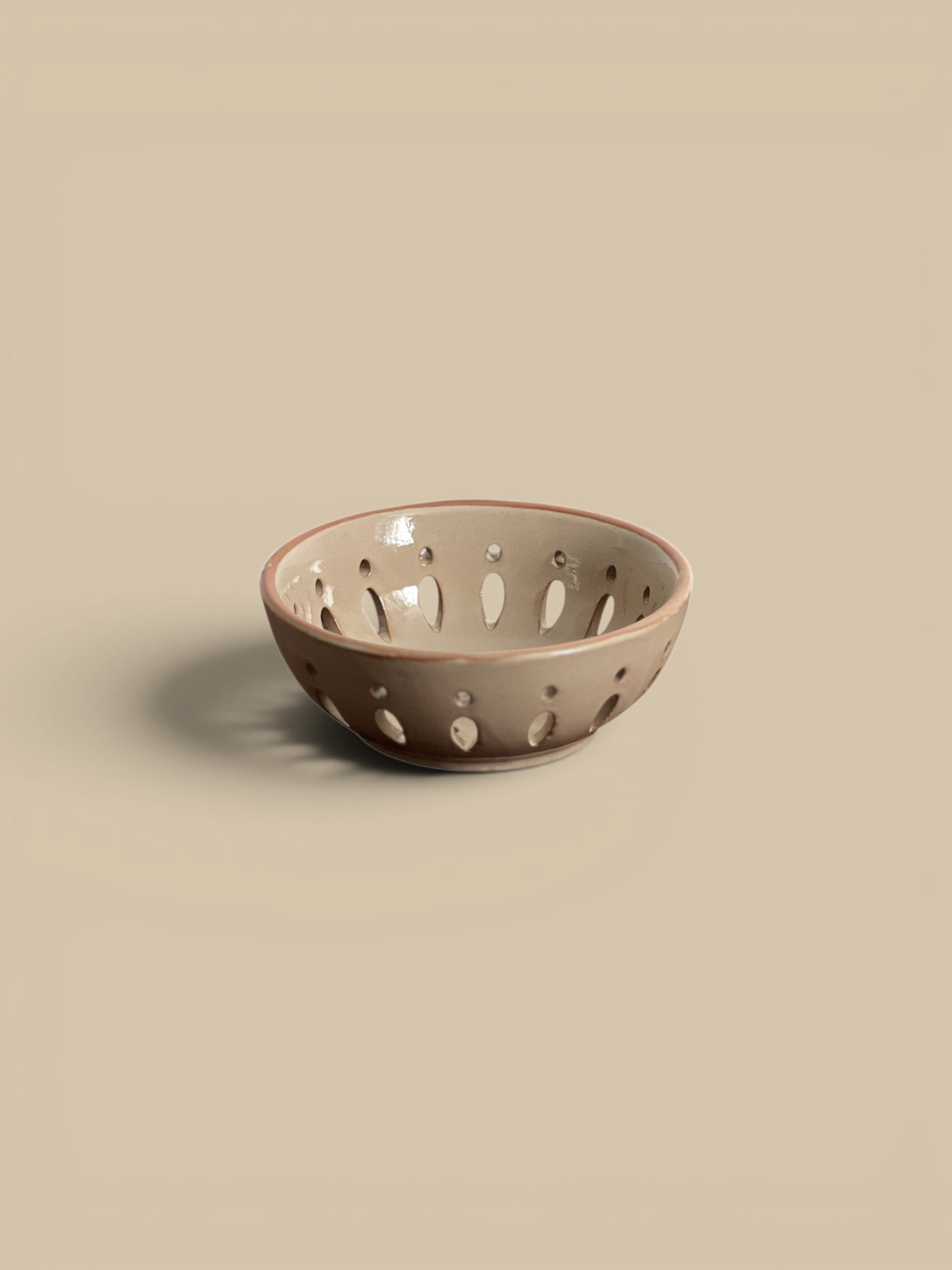 Homestyle Collective sand ceramic bowl with cut-out details for draining fruit. 5" round.