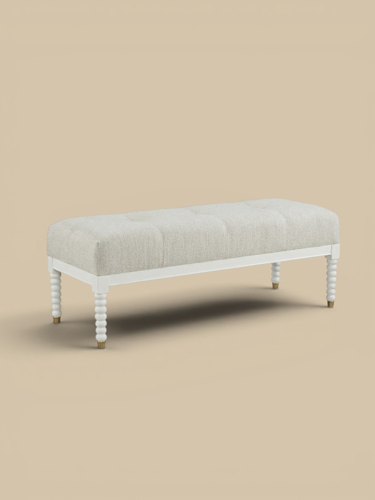 Homestyle Collective Sienna bench with tufted light beige linen upholstery and white turned legs with brass accents.