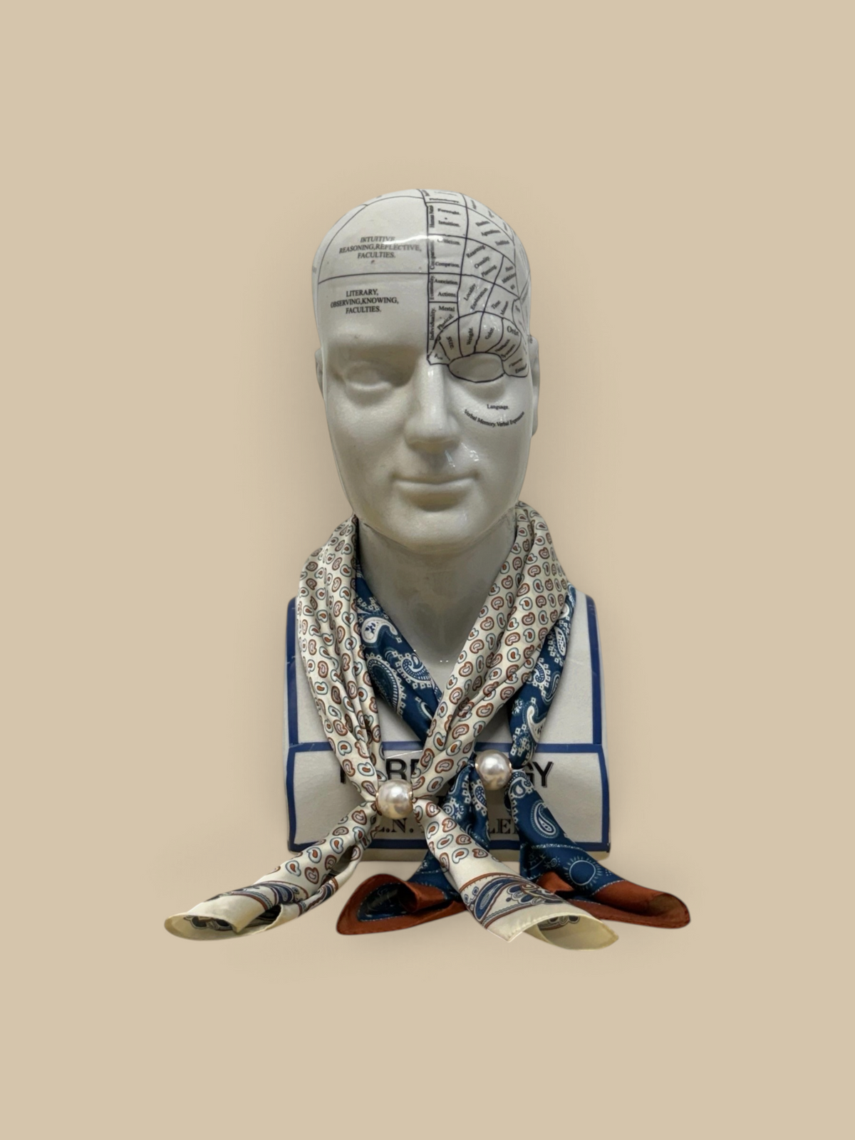 Homestyle Collective silk neckerchief scarf in navy and beige paisley with a magnetic pearl closure on a phrenology head