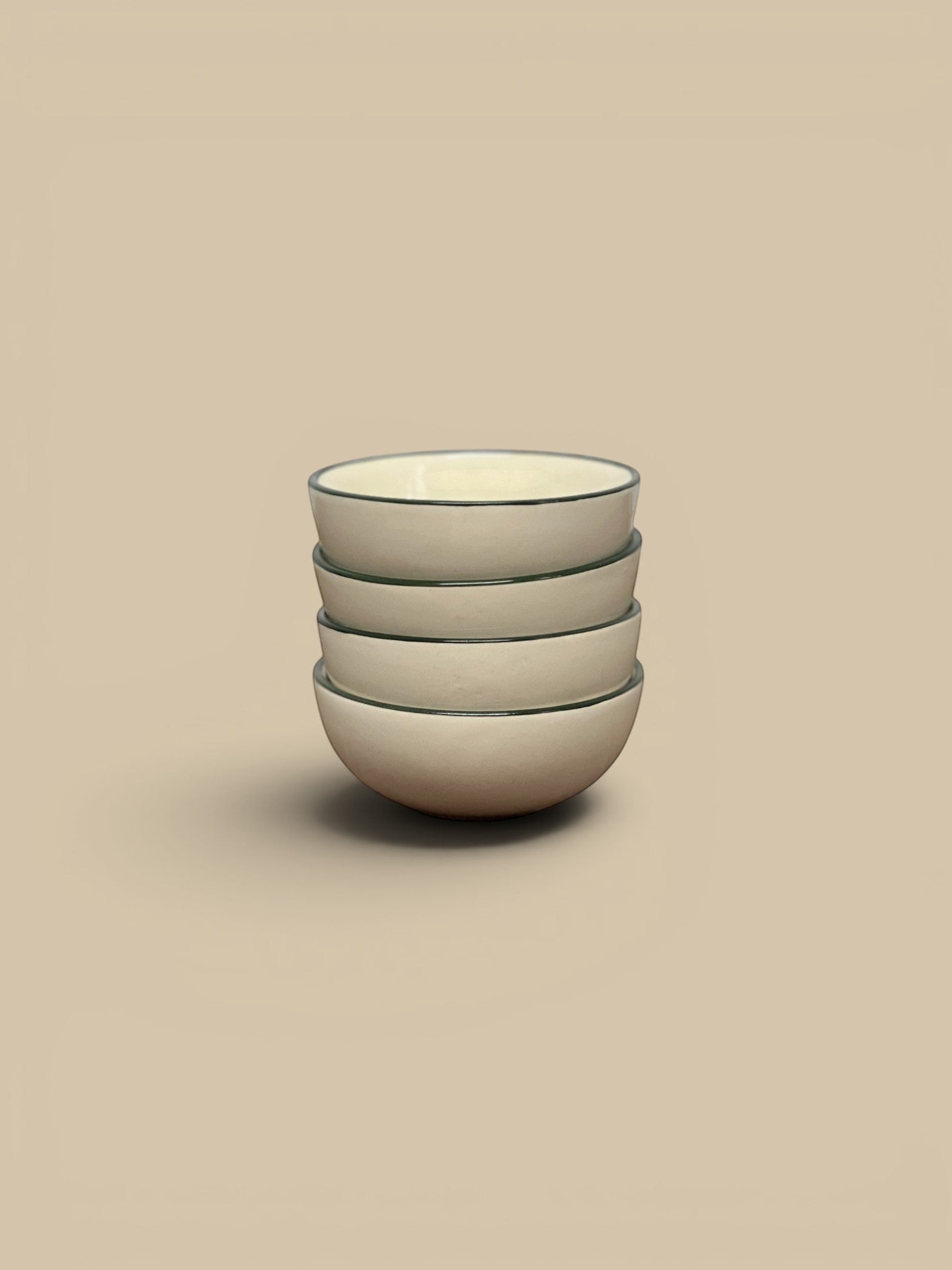 Homestyle Collective stack of four cream stoneware bowls with a thin green rim detail, perfect for snacks or display.
