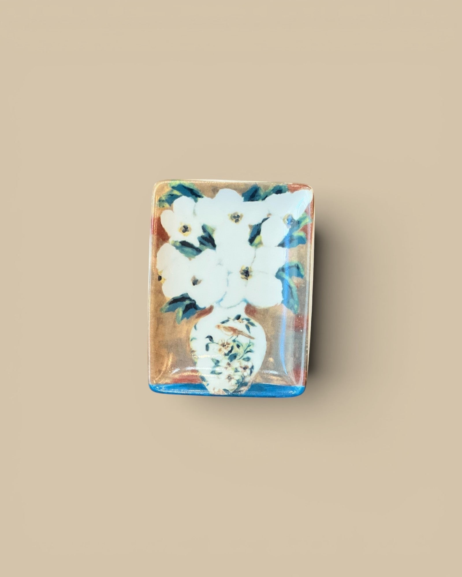 Homestyle Collective stoneware tray with a still-life painting of white flowers in a vase. Features a gold background and blue trim.