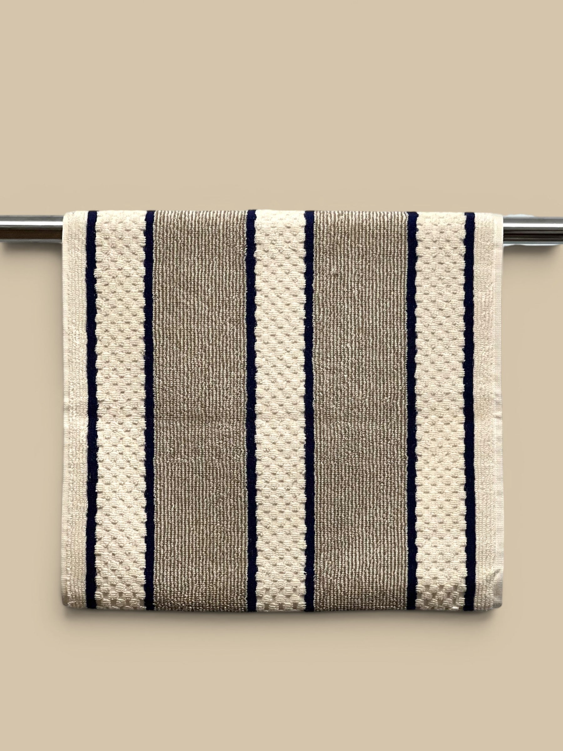 Homestyle Collective cream, taupe, and navy striped cotton hand towel with popper fastening for hanging.