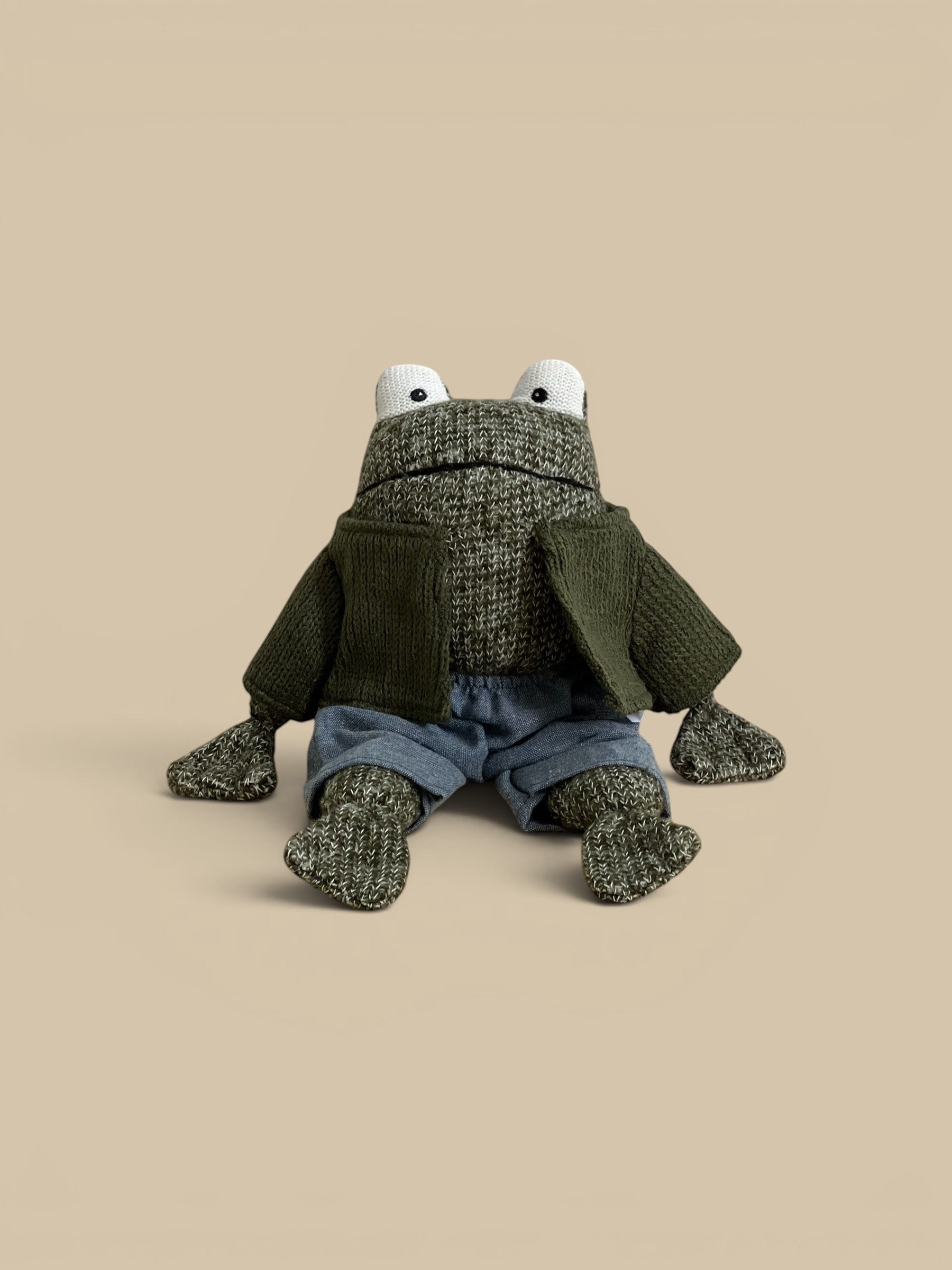 Homestyle Collective stuffed cotton frog toy wearing a green knit cardigan and blue shorts with a stitched face.