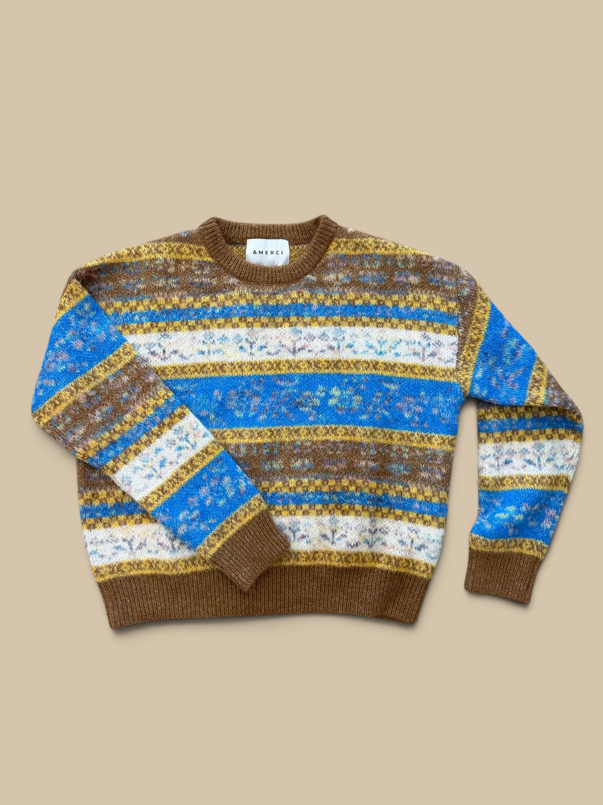 Homestyle Collective toffee fair isle sweater with vibrant blue, yellow, and white floral patterns on a wooden floor.