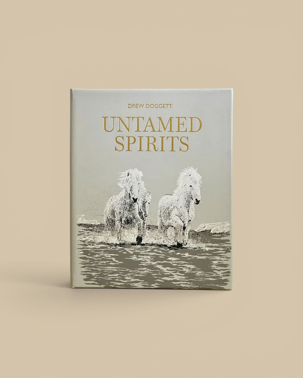 Homestyle Collective Untamed Spirits coffee table book featuring a grey cover with gold text and wild horses imagery.
