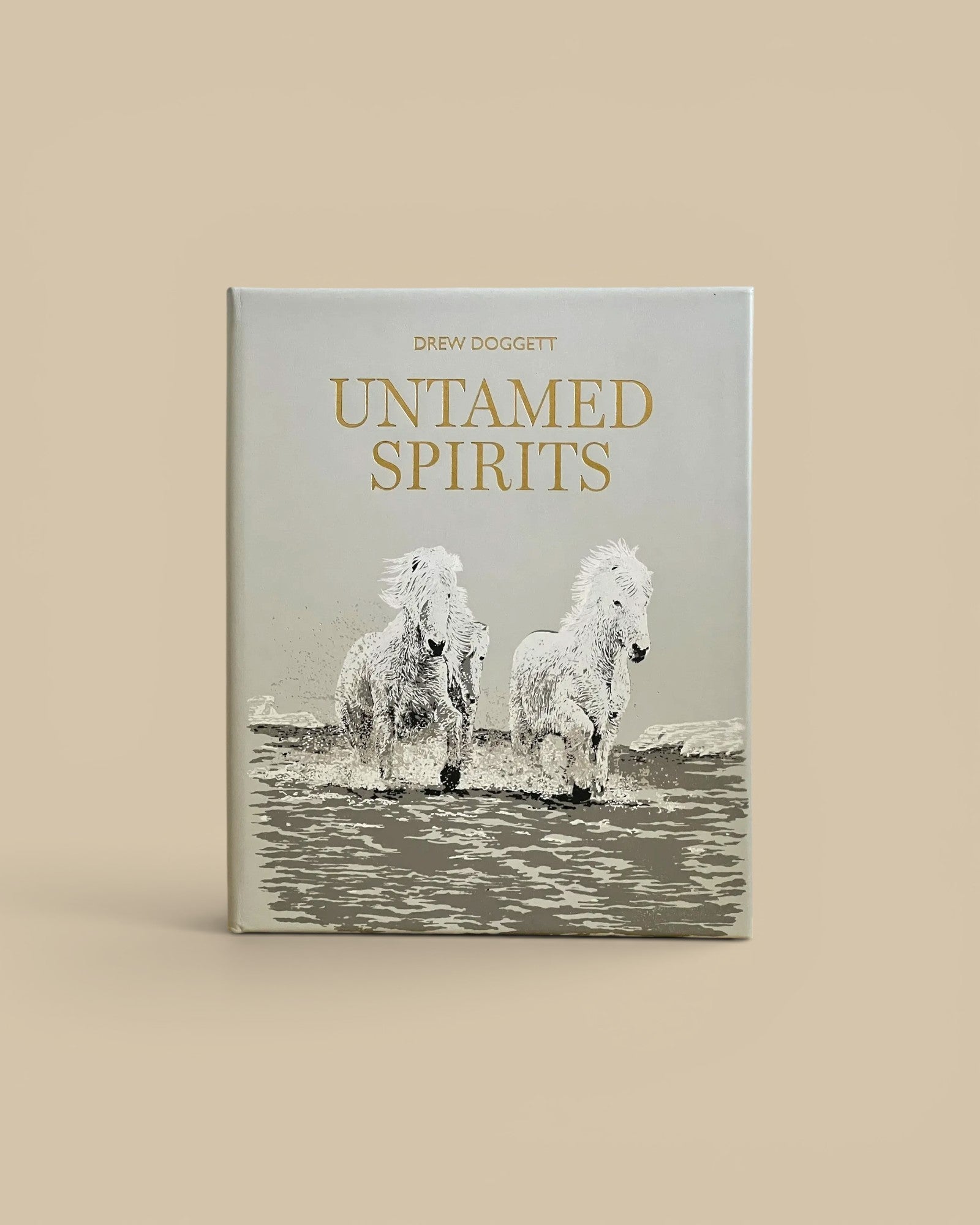Homestyle Collective Untamed Spirits coffee table book featuring a grey cover with gold text and wild horses imagery.