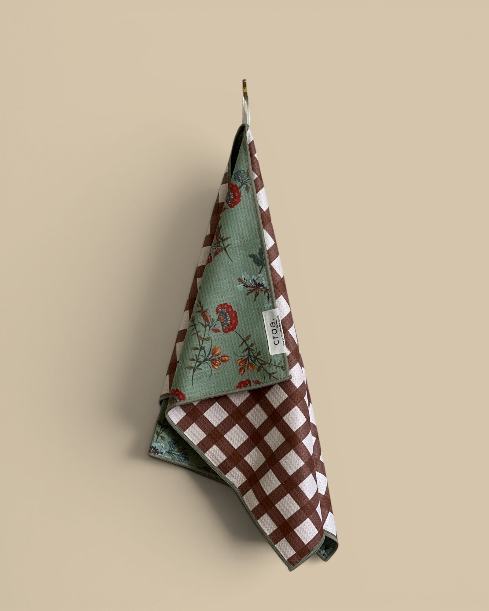 Homestyle Collective reversible waffle weave hand towel with floral print on one side and brown & white check on the other.