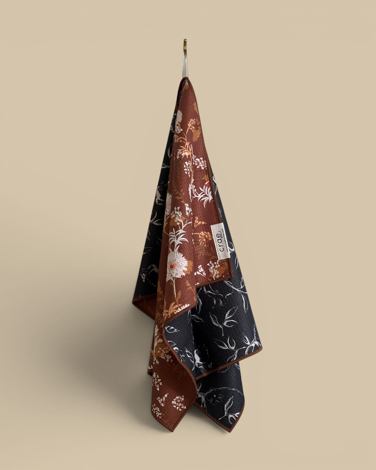 Homestyle Collective waffle weave hand towel with floral print in brown and black.