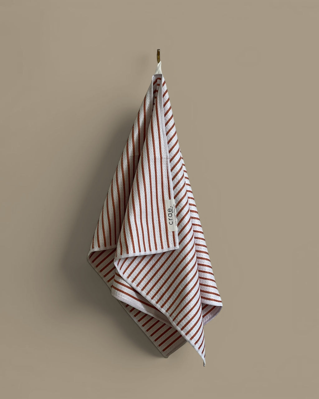 Homestyle Collective white waffle weave hand towel with rust-colored stripes and a textured finish.